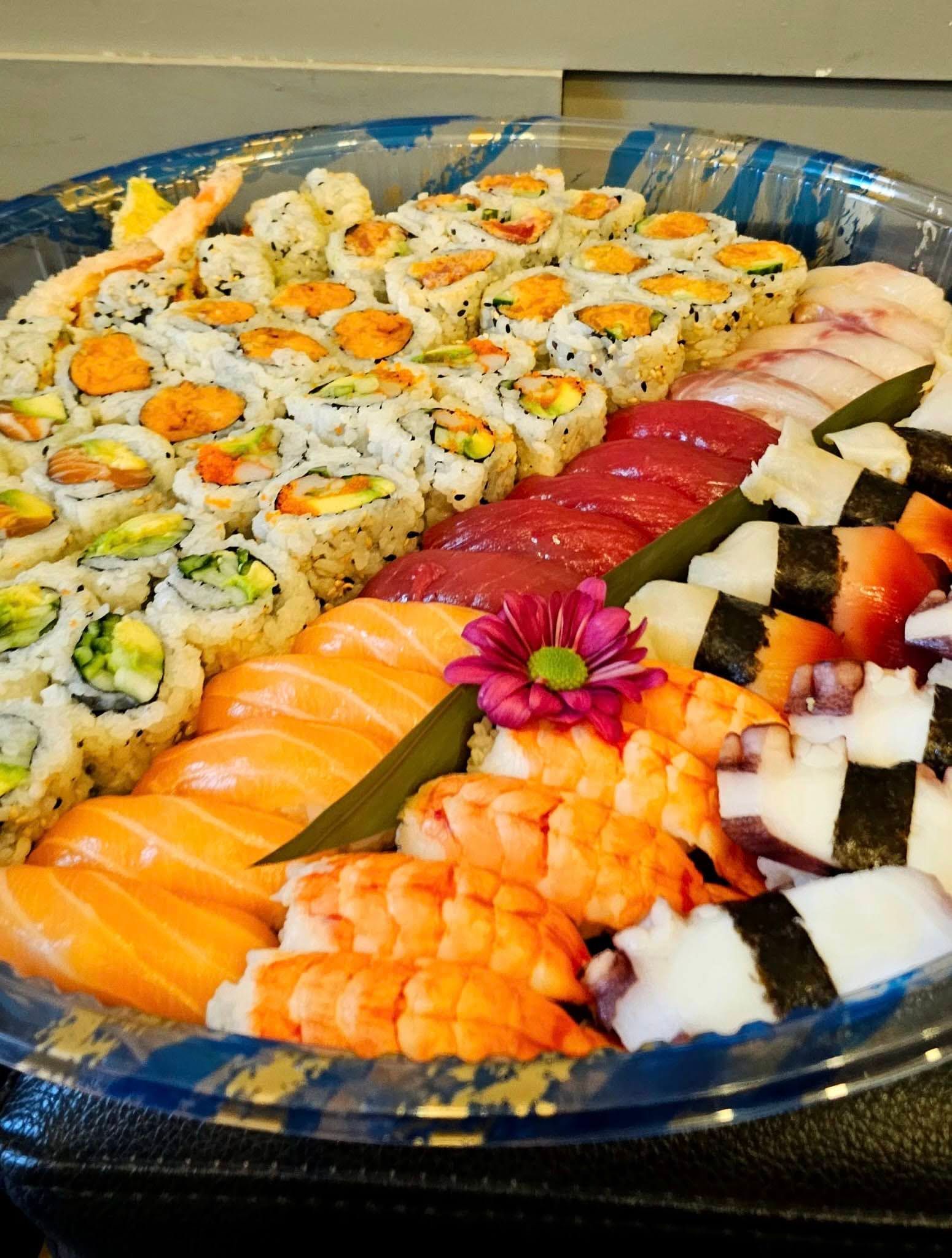 Assorted sushi rolls and nigiri arranged on a platter, with orange salmon, red tuna, and white garnishes.
