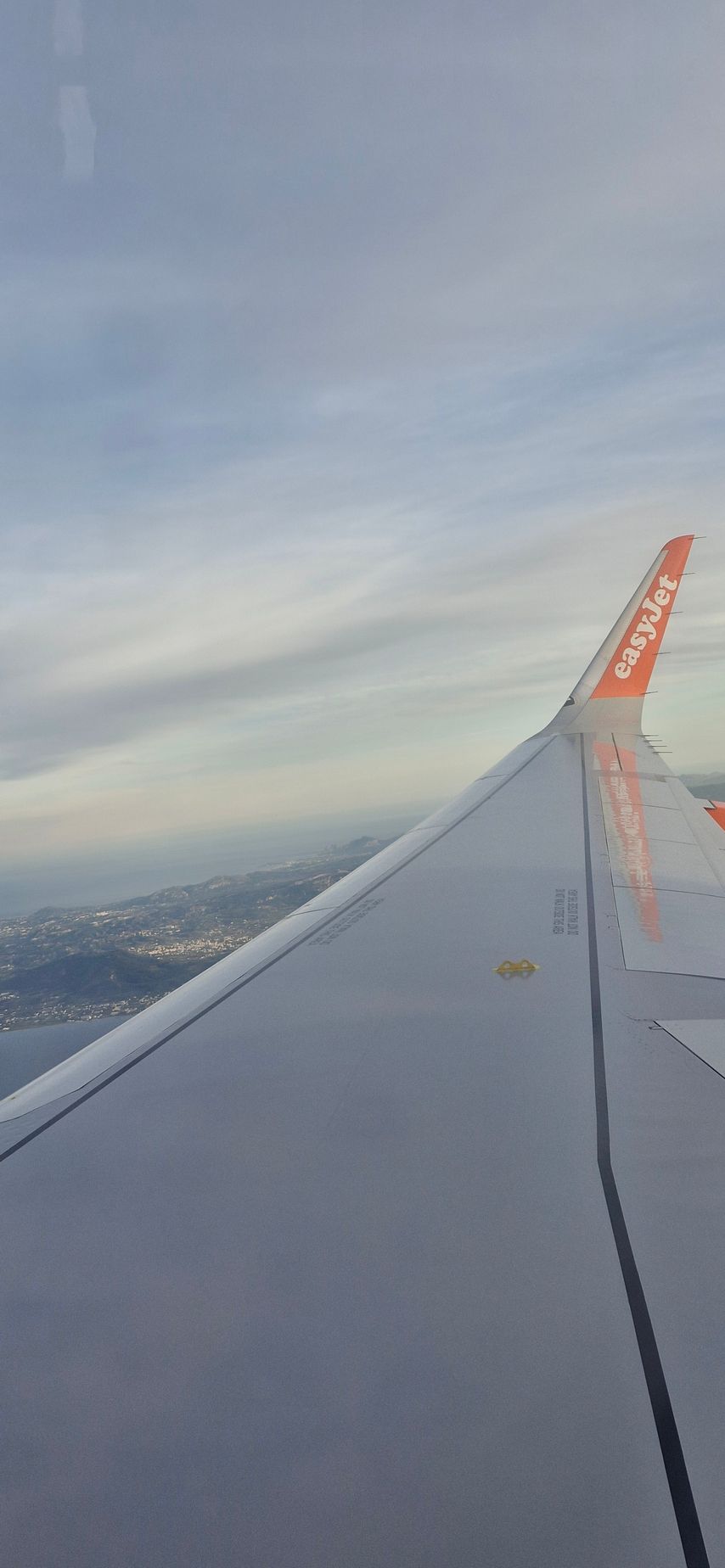 A close up of the wing of an airplane flying in the sky.
