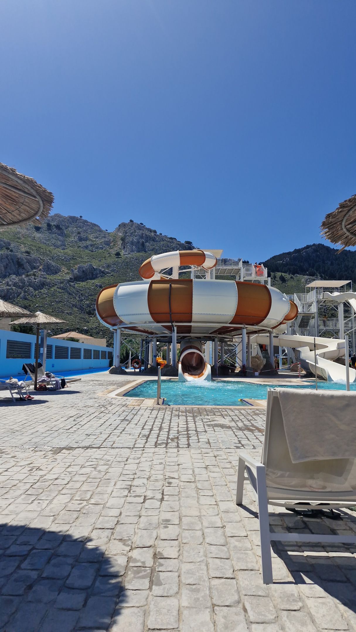 There is a water slide in the background and a pool in the foreground.