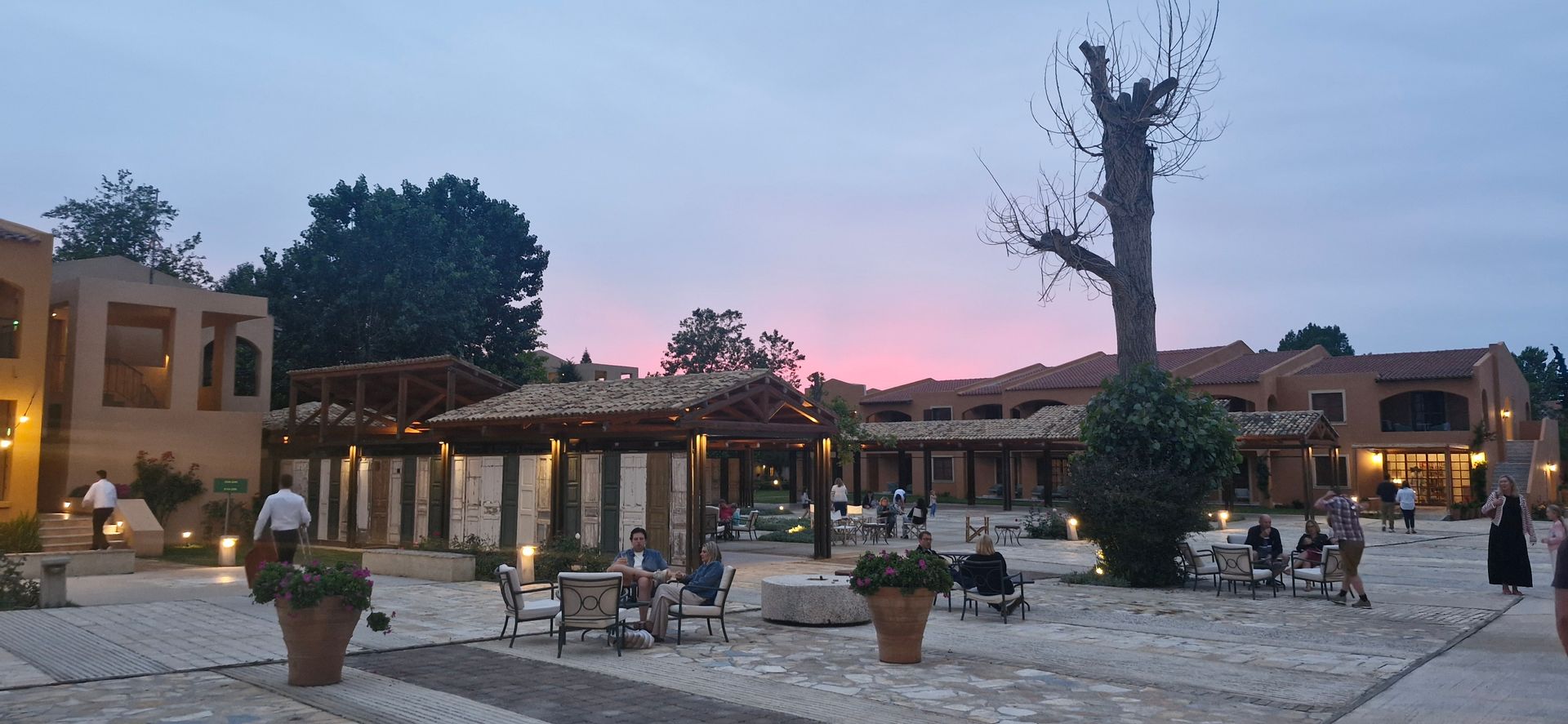 A group of people are sitting outside of a building at sunset.