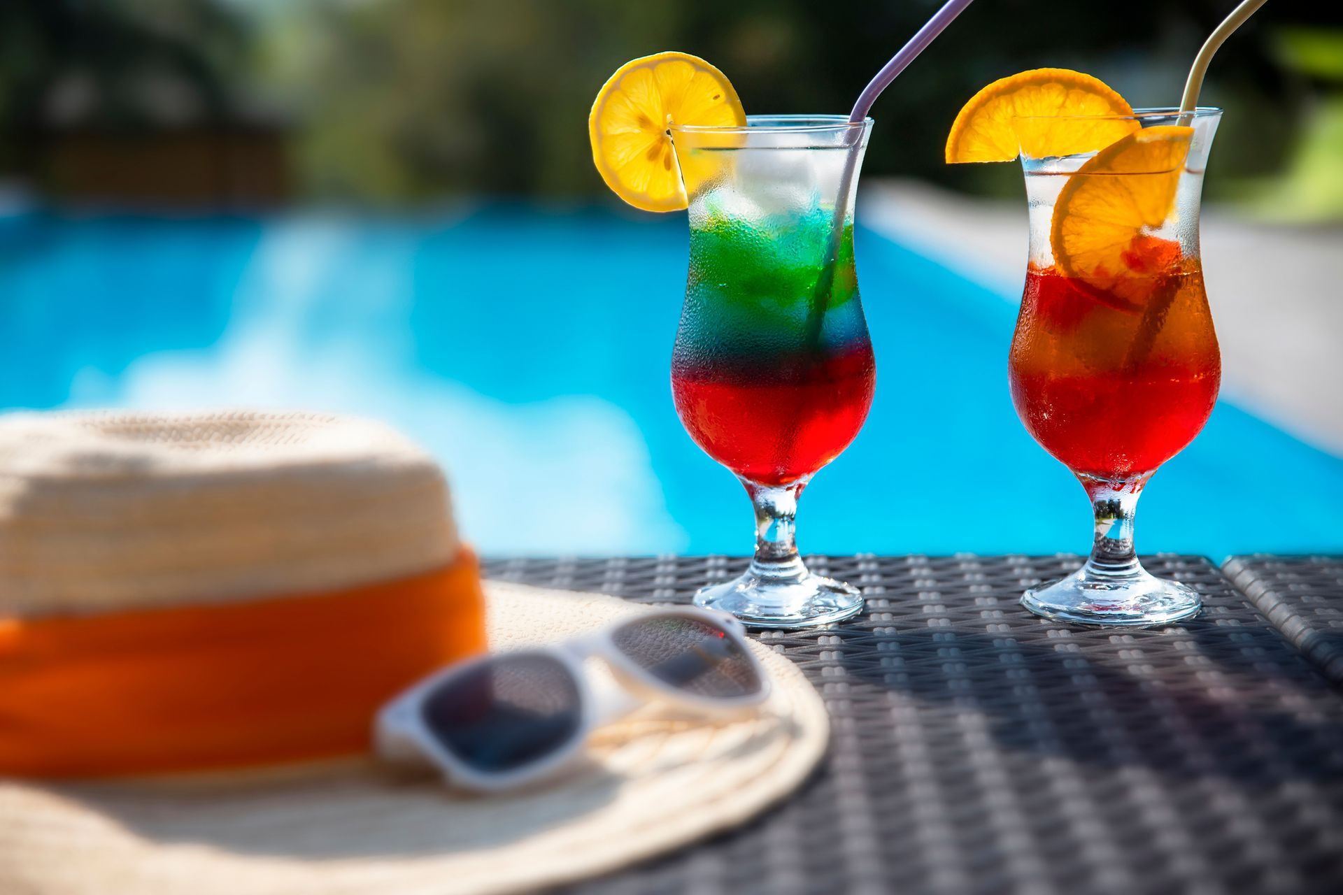 All Incluisve Two drinks are sitting on a table next to a hat and sunglasses.