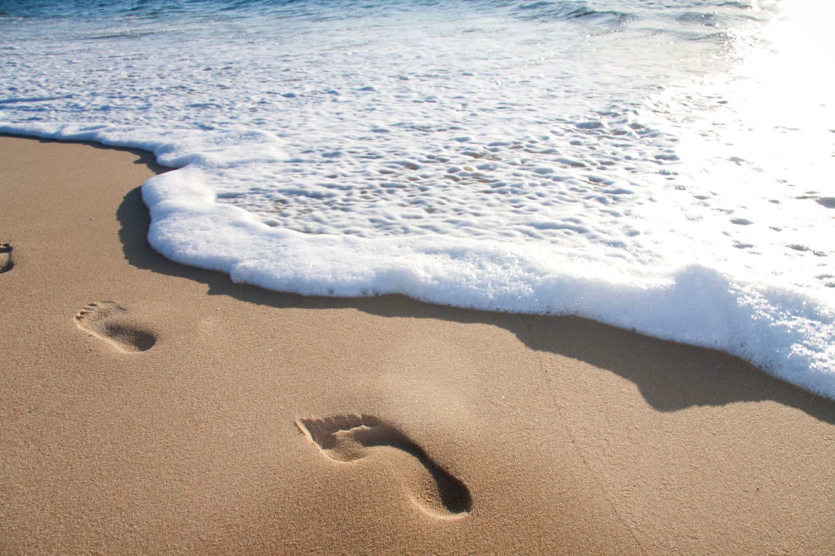 Close-up of a barefoot footprint pressed into the sand 