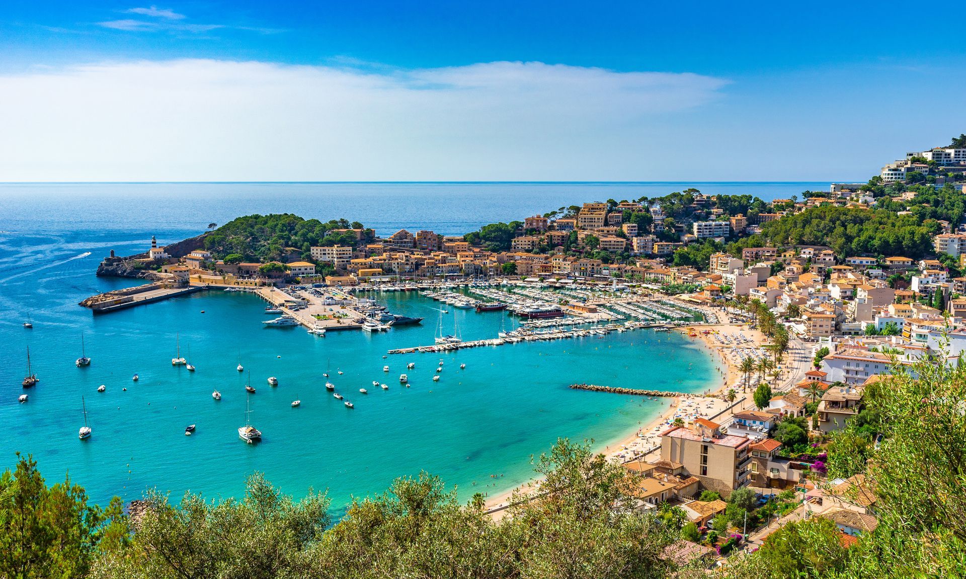 Majorca An aerial view of a beach with boats in the water and a city in the background.