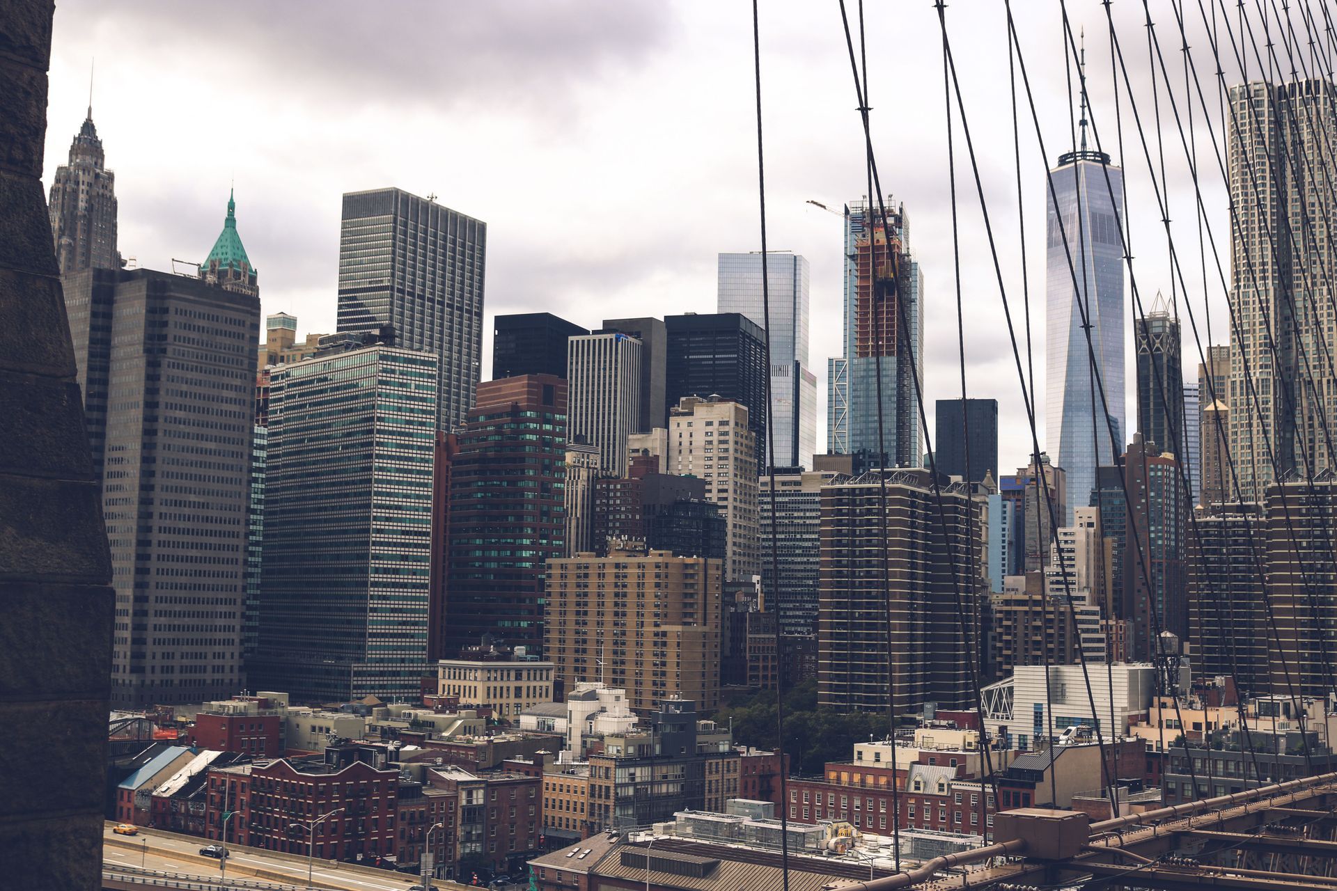 New York City skyline viewed through suspension bridge cables at dusk