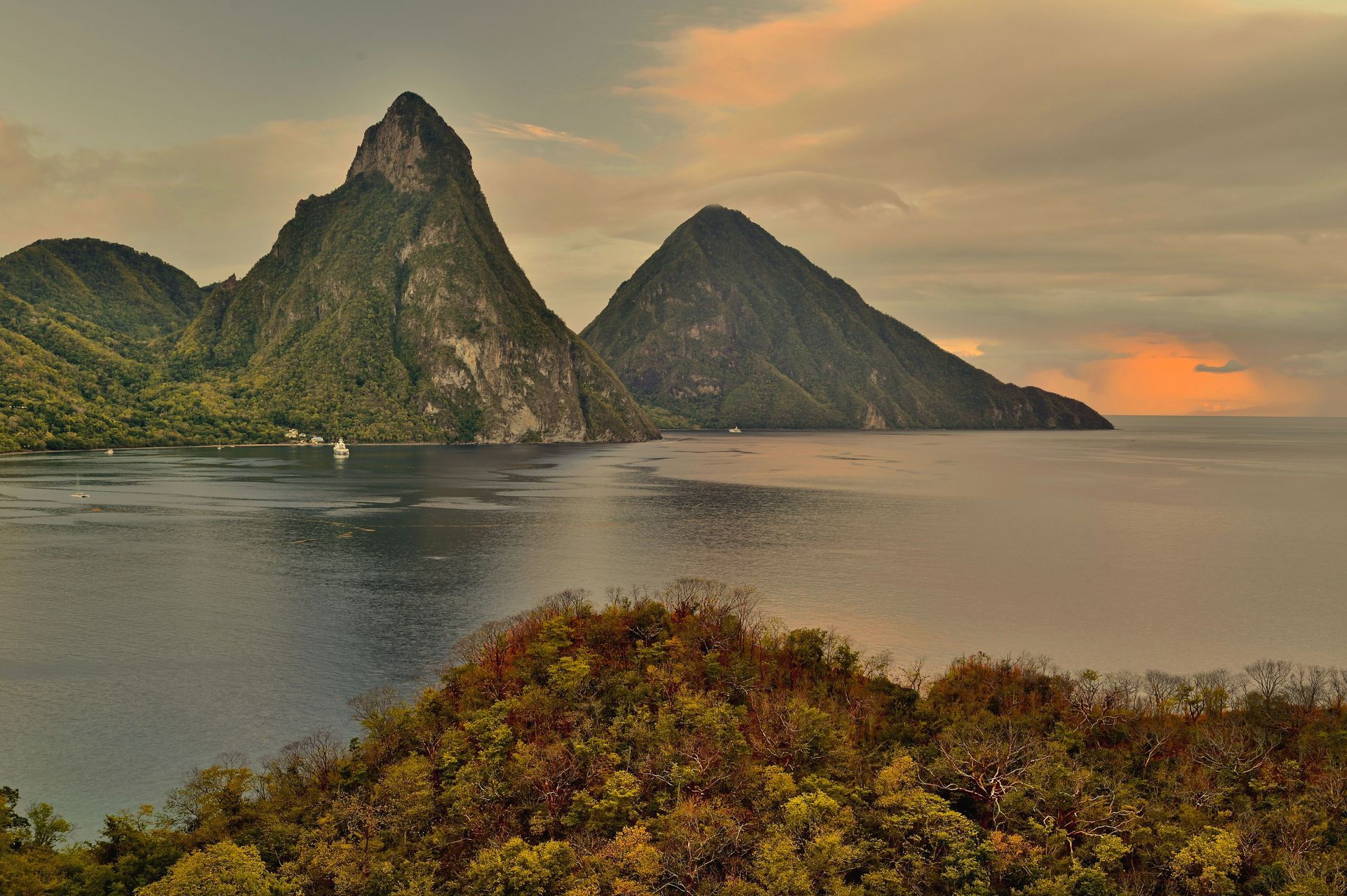Sunset over a tropical bay with twin green mountains and calm water