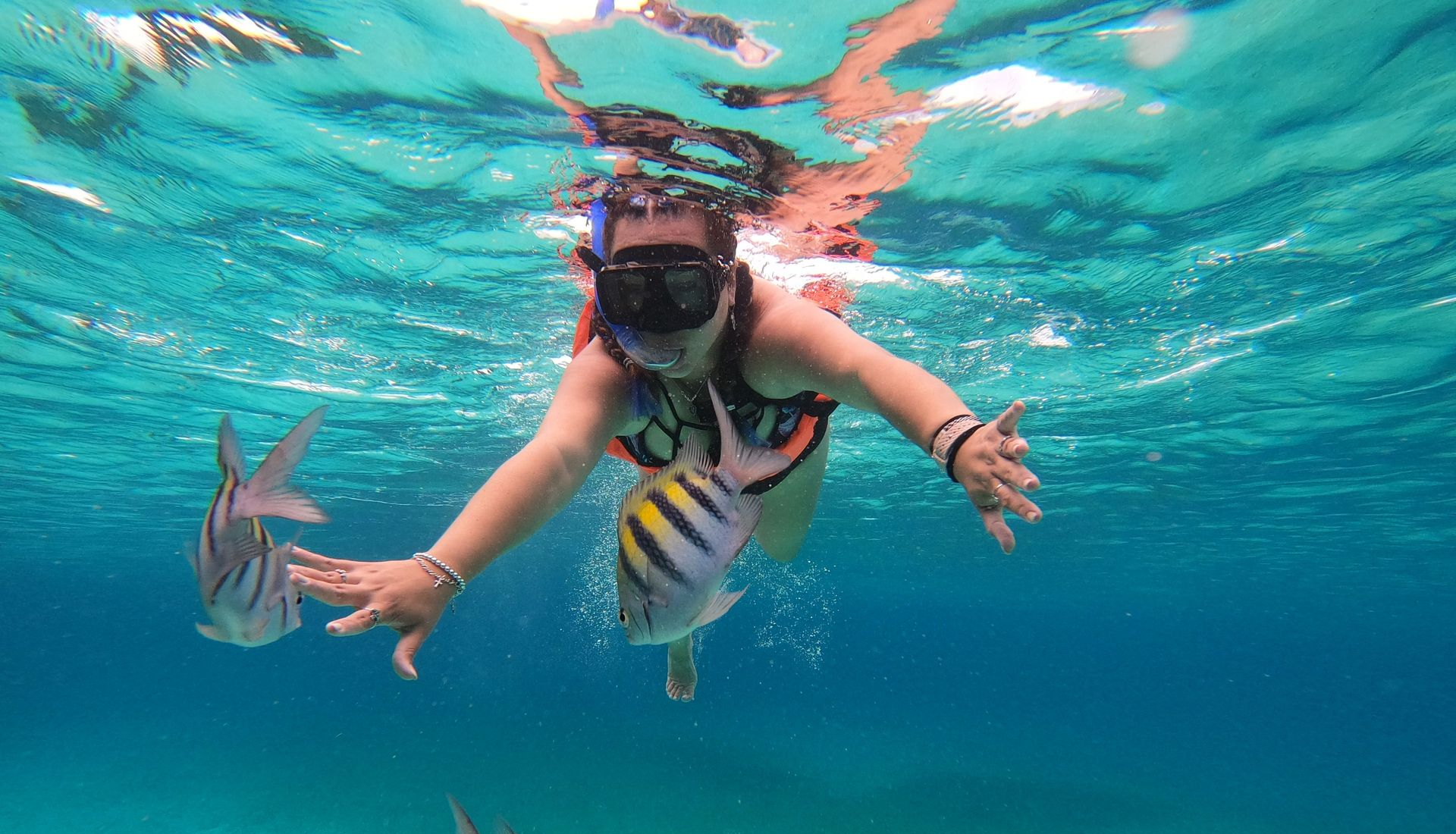 Snorkeler swimming underwater near colorful fish in clear turquoise water