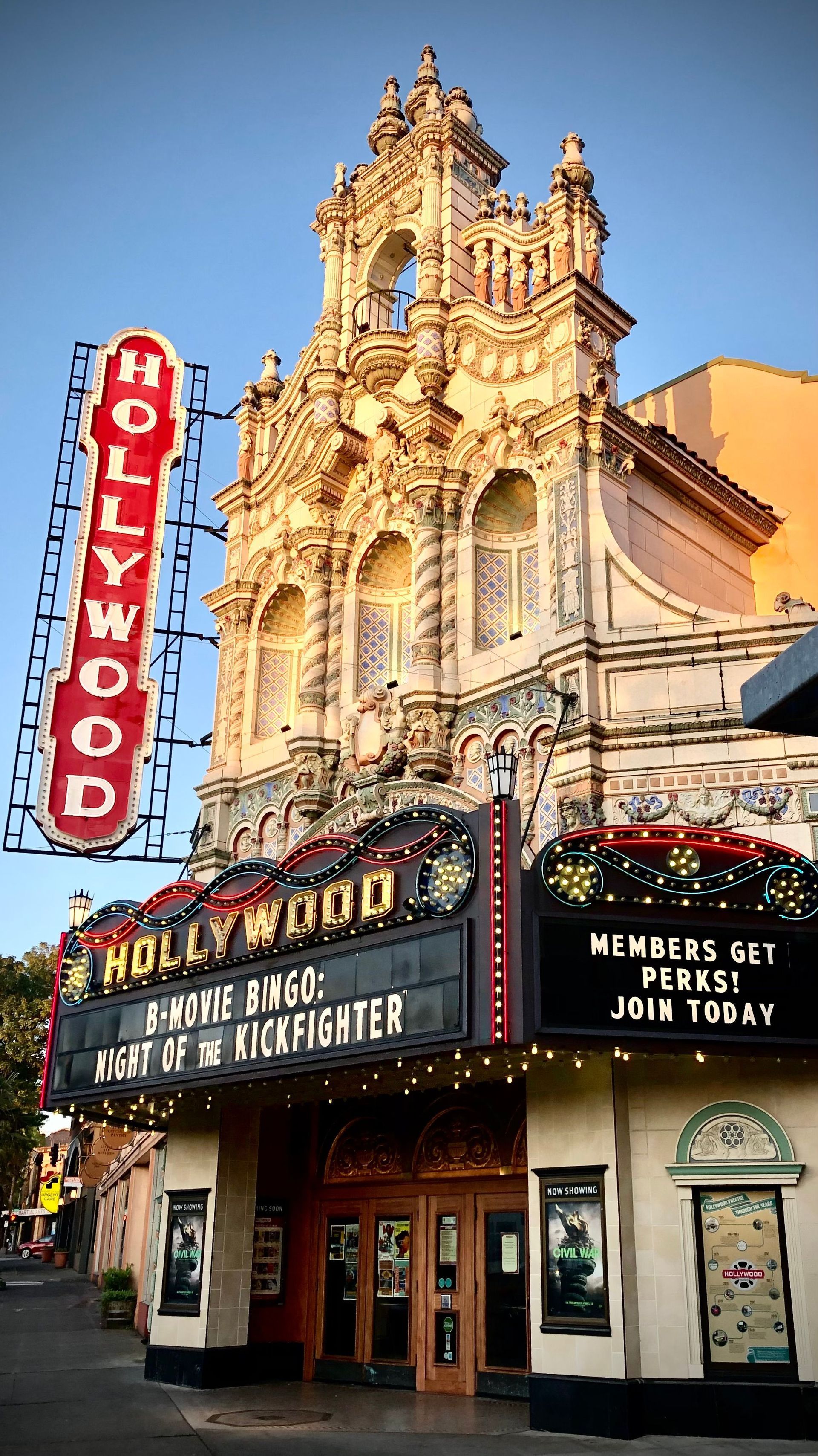 Hollywood Theatre marquee beneath ornate gold facade and red vertical HOLLYWOOD sign at dusk