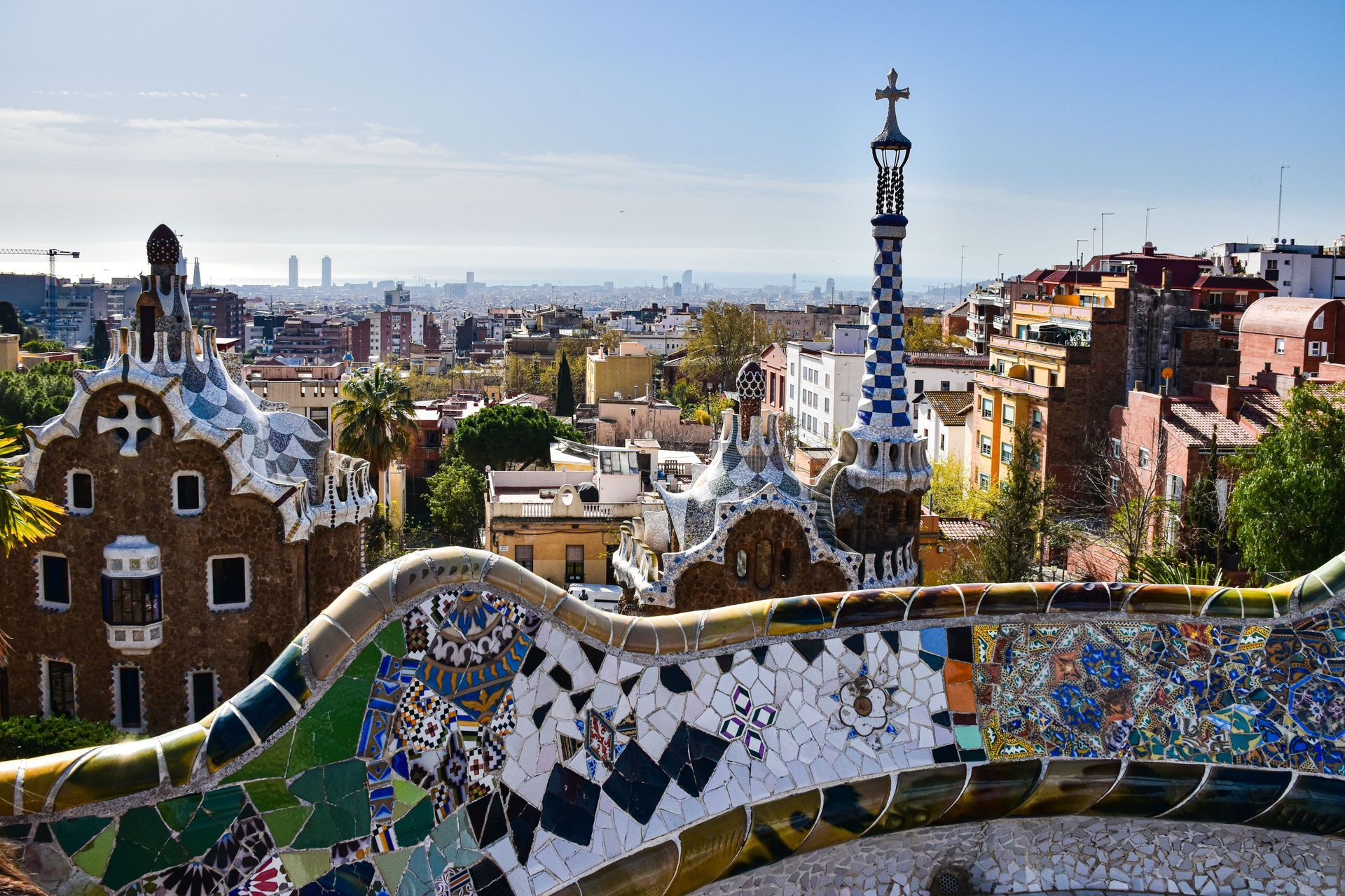 Colorful mosaic terrace overlooking Barcelona skyline under a clear blue sky