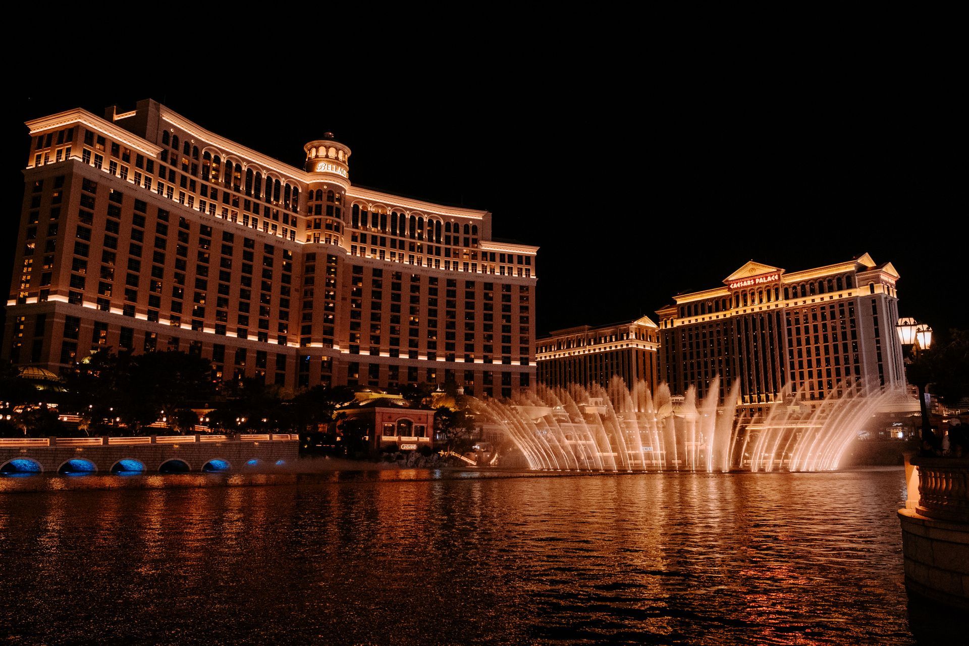 Bellagio Hotel and fountains glowing at night with water jets arcing over the lake