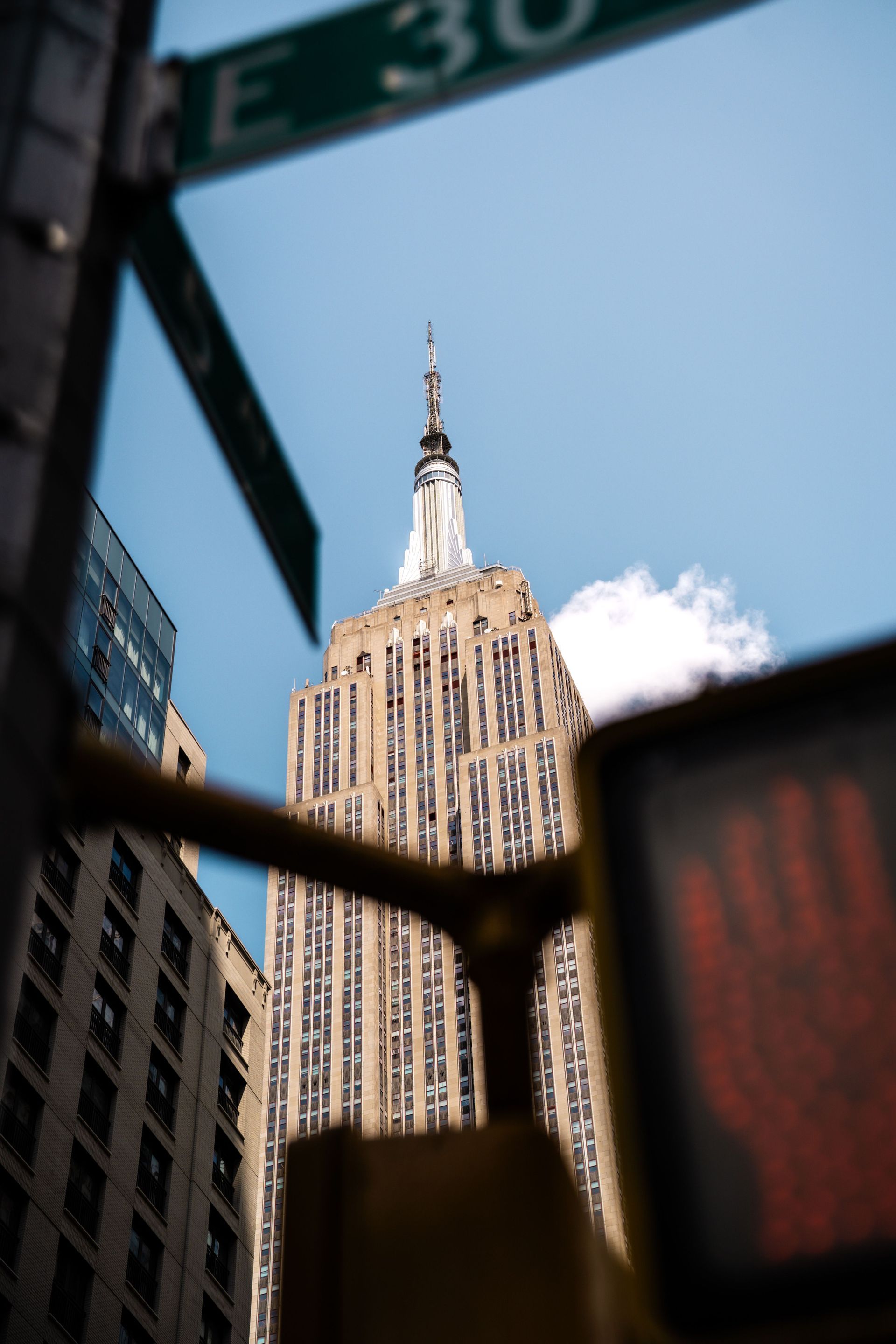 Empire State Building framed by dark structures against a blue sky