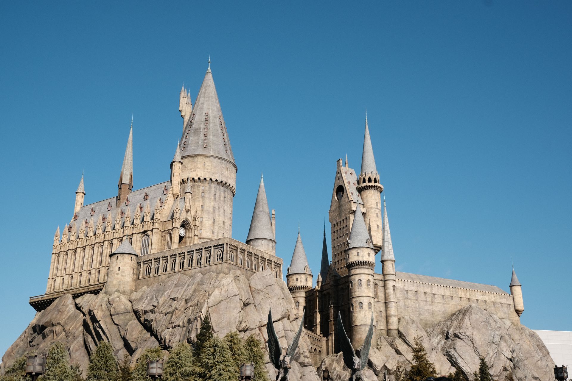 Stone castle with tall spires perched on a rocky hill under a clear blue sky