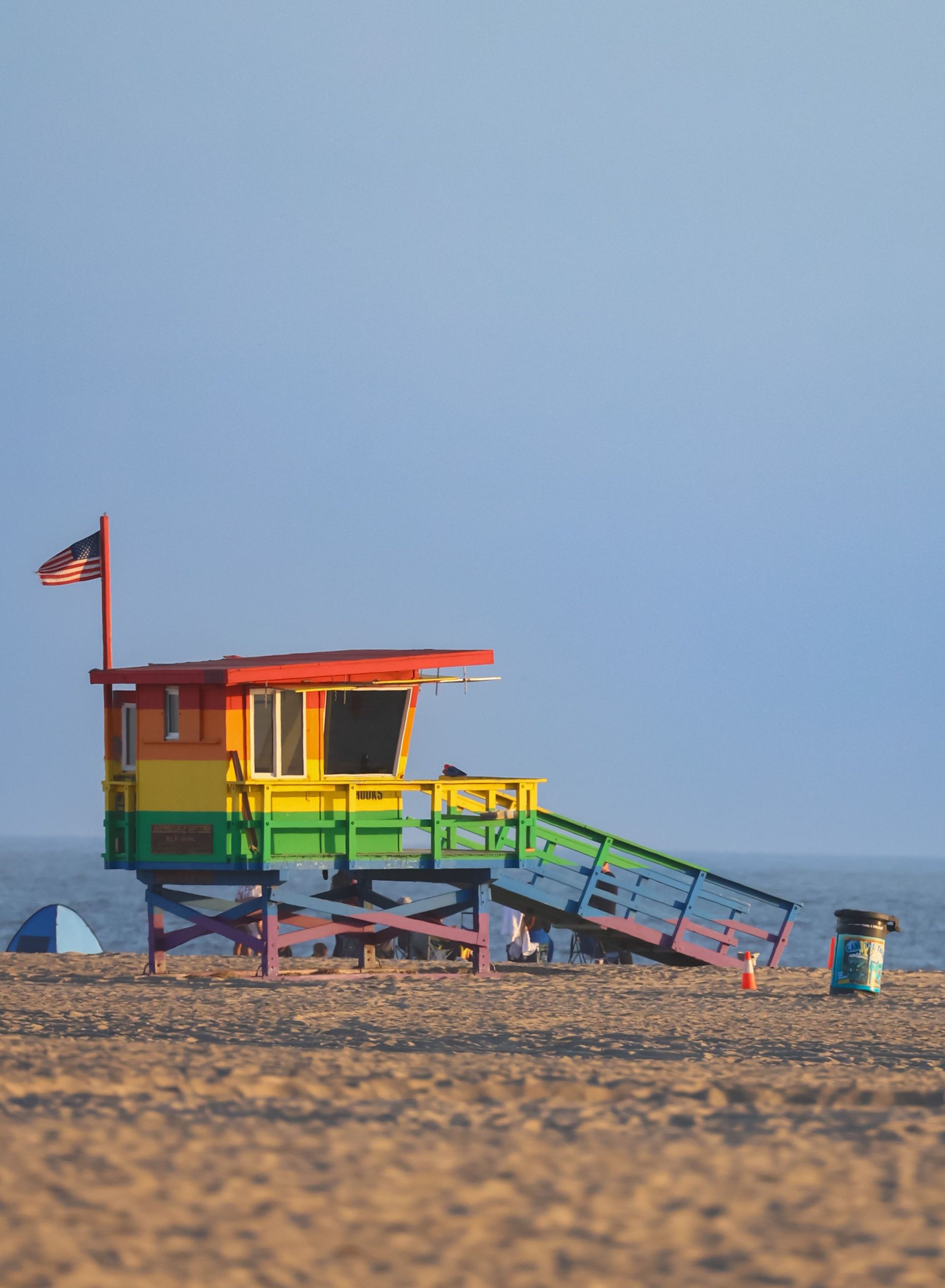 Colorful beach lifeguard tower with ramp on sandy shore under a clear blue sky