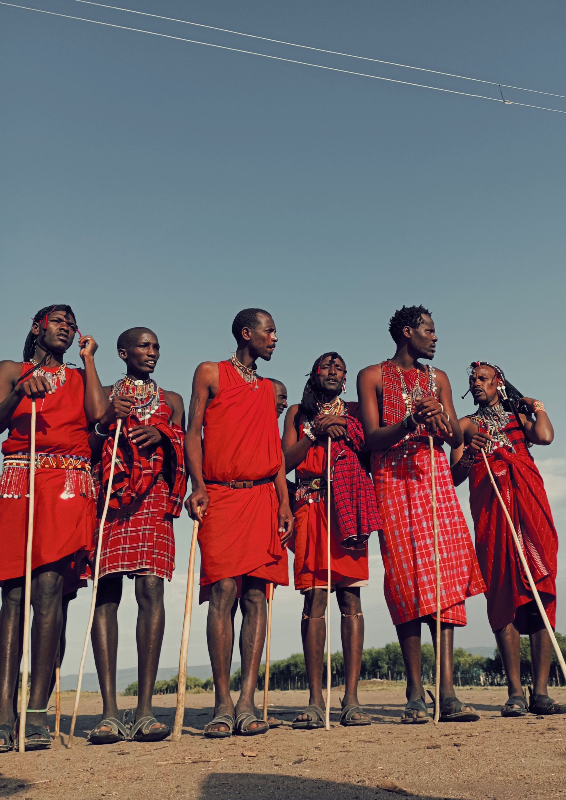 Group of people in red traditional clothing standing outdoors under a blue sky.