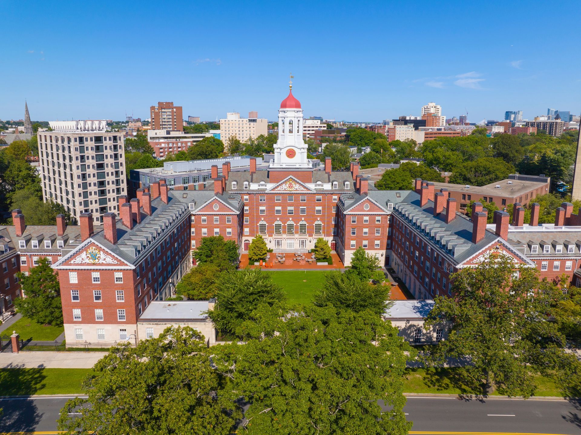 Historic white capitol building framed by trees at the end of a brick walkway