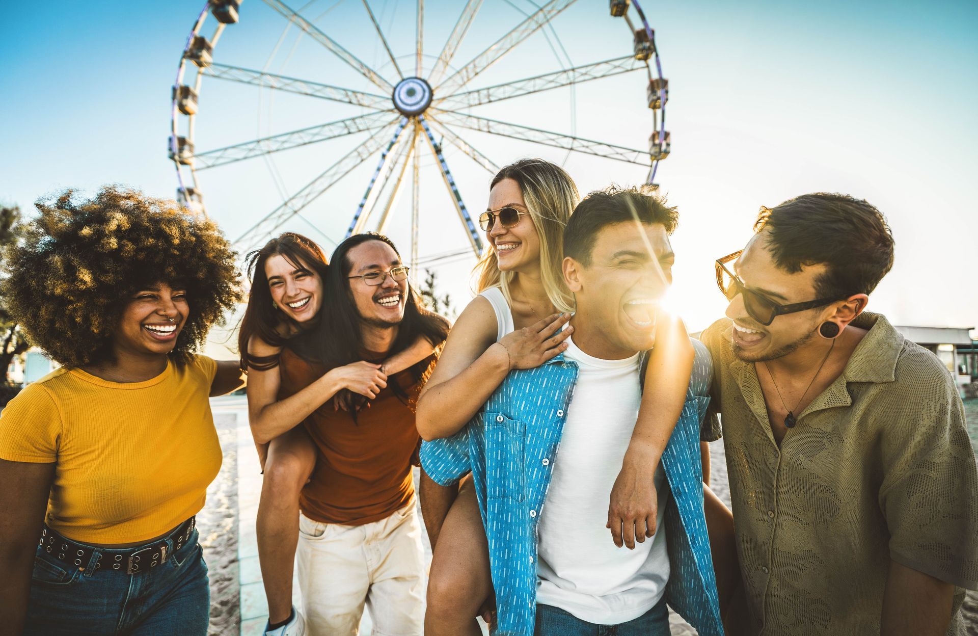 Friends smiling at a carnival with a Ferris wheel in the background