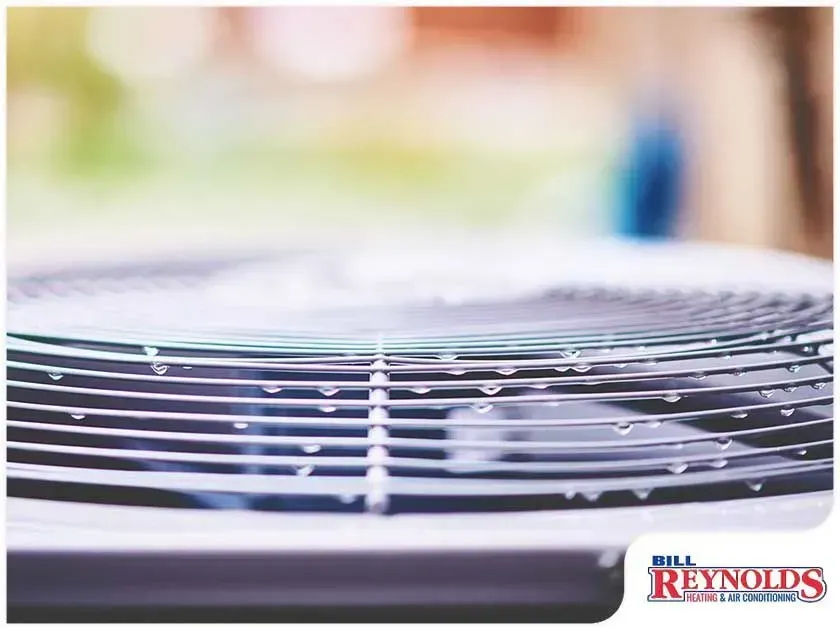 Close-up of an air conditioning unit with condensation on the metal fins outside.