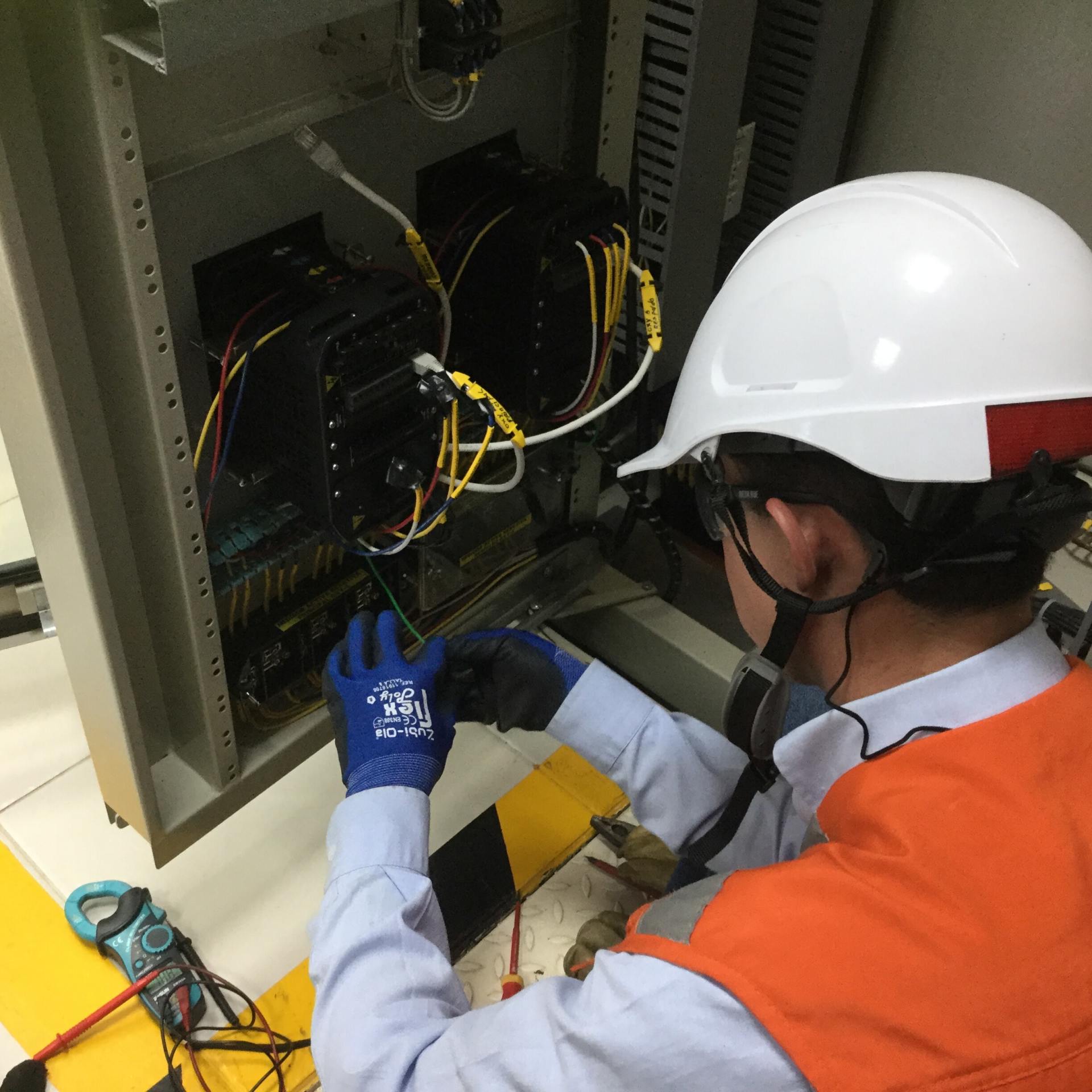 Un hombre que lleva un casco está trabajando en una caja eléctrica.