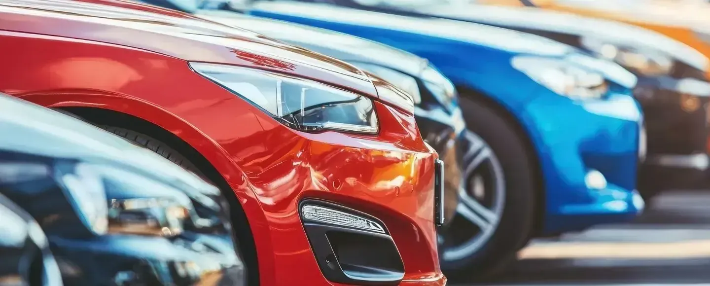 A close-up of a line of parked cars, focusing on a bright red vehicle in the foreground.