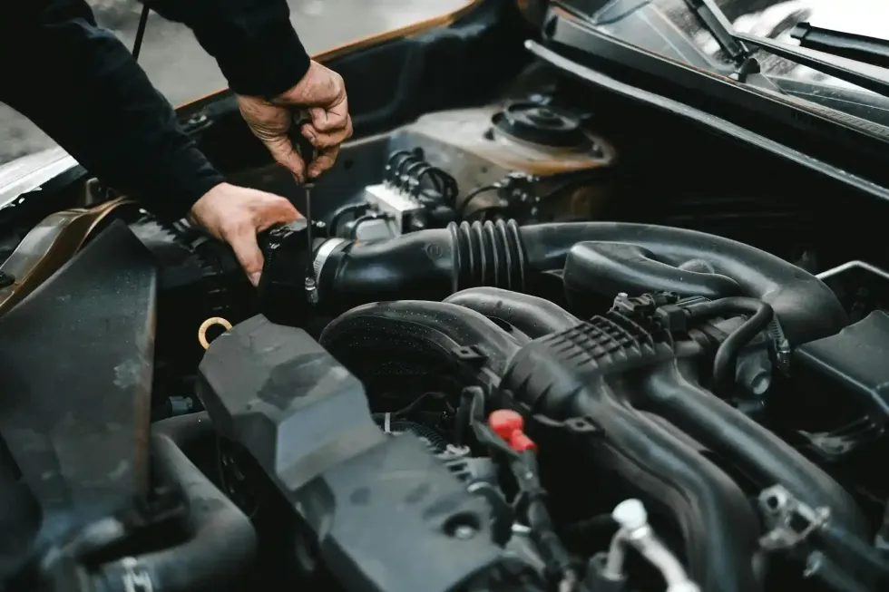A mechanic using a screwdriver to work on a car engine.