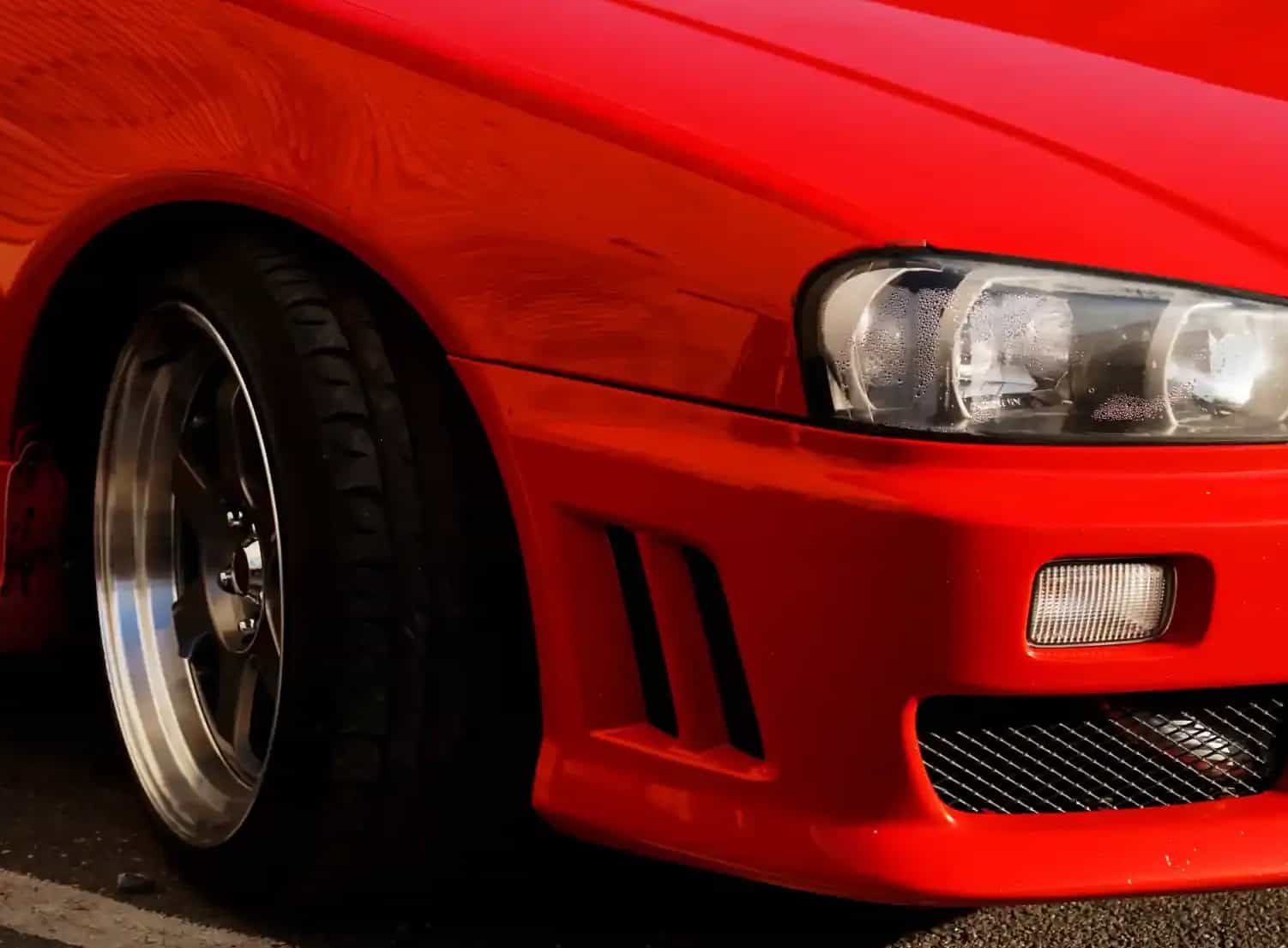 A bright red Mitsubishi Galant parked outdoors on a paved lot with a blurred background.