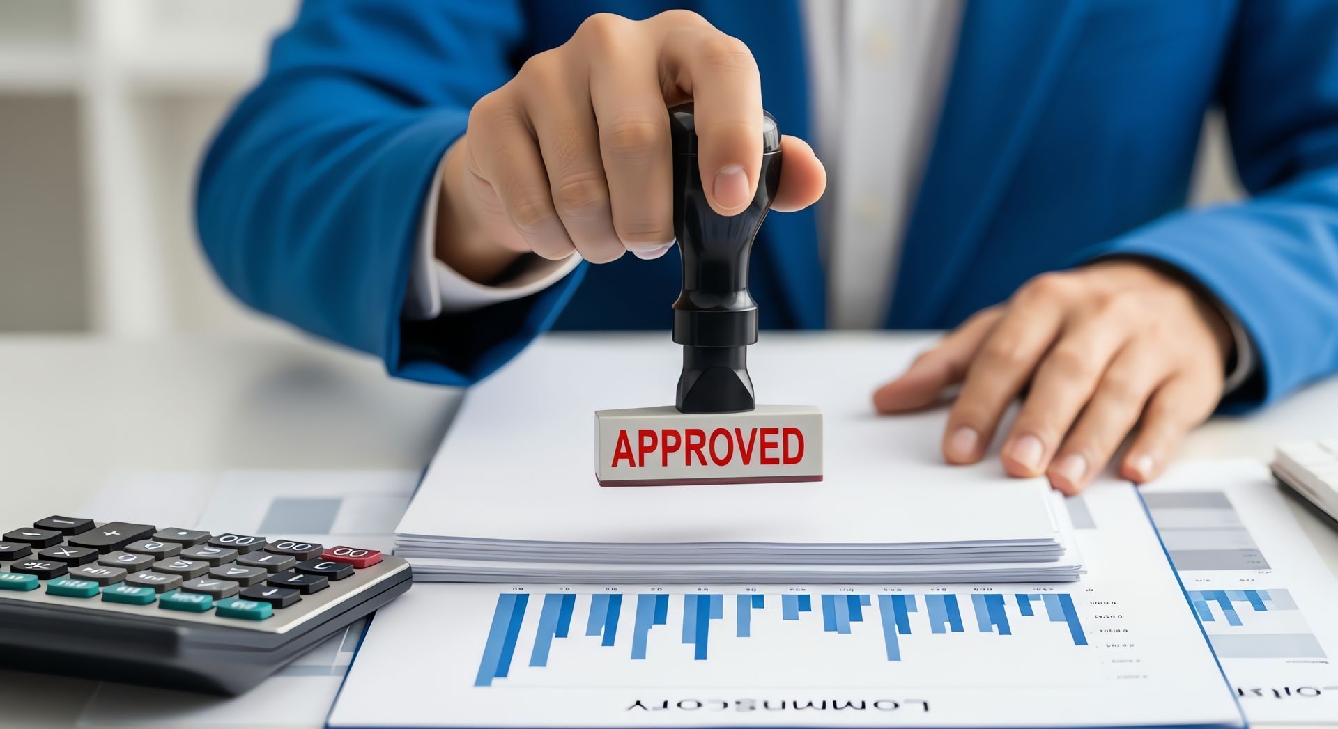 A person in a blue suit uses a rubber stamp that reads 