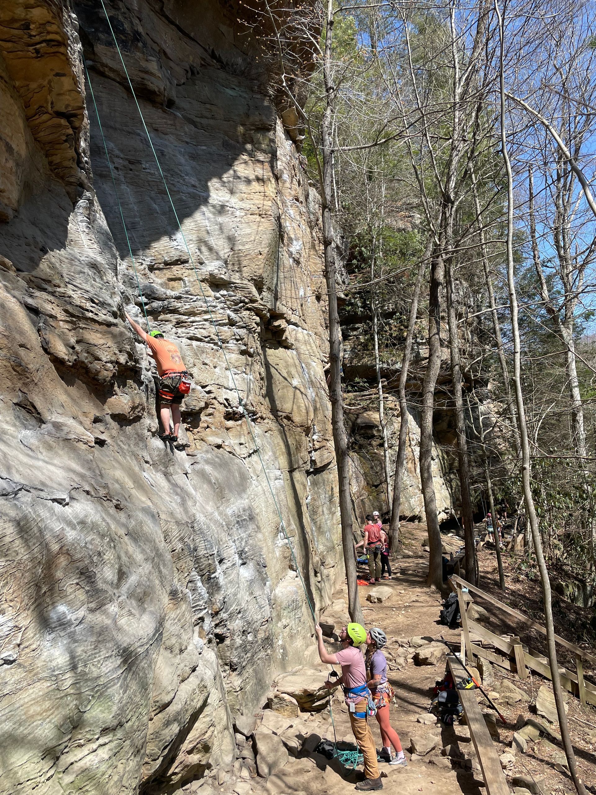 Climber brushing chalk tick marks off a sandstone route in the Red River Gorge