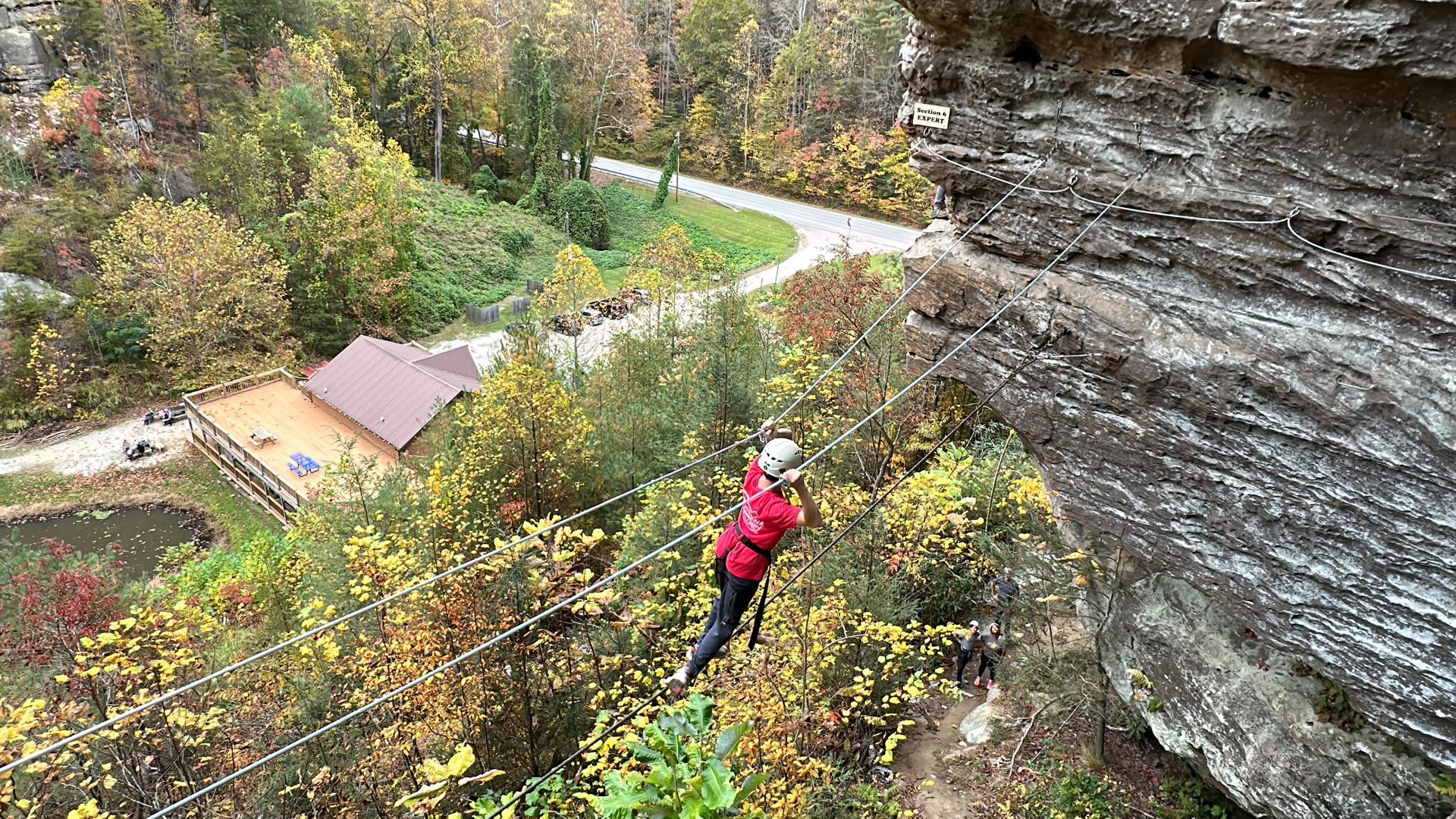 Climber wearing closed-toe shoes and gloves clipped into the Red River Gorge Via Ferrata cable bidge