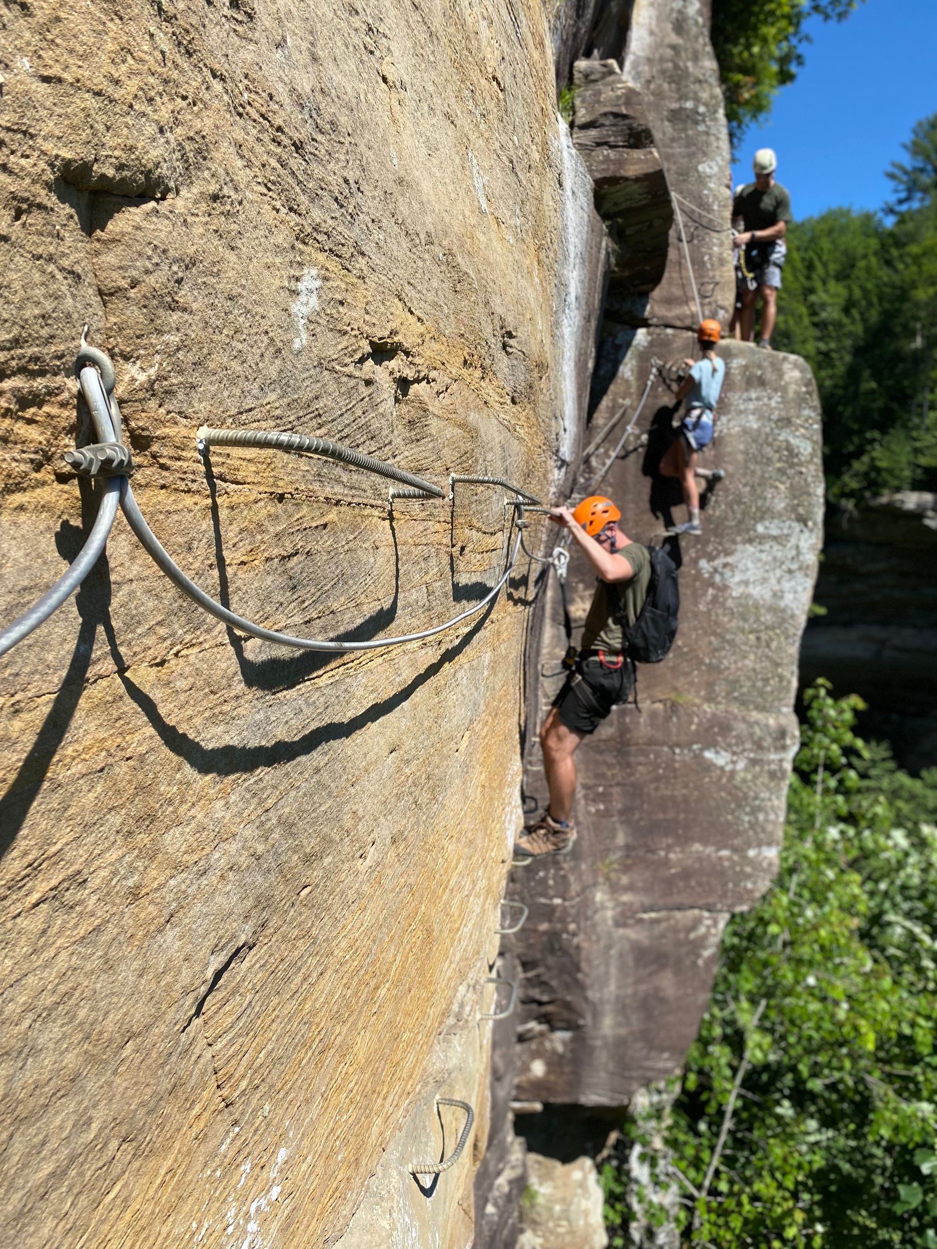 climbers hang onto via ferrata rungs as they complete the kentucky tenessee via ferrata at southeast mountain guides