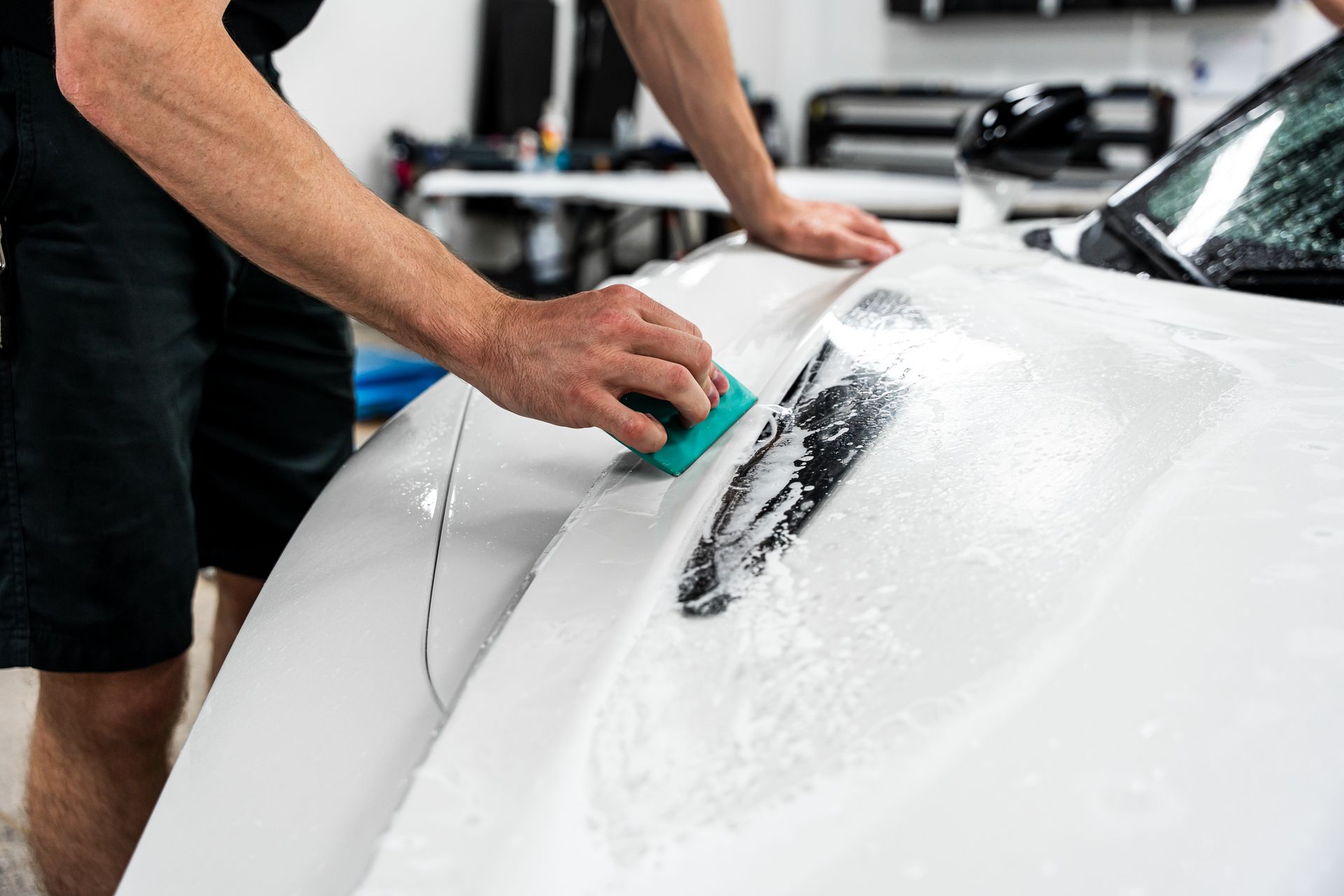 Person cleaning a white car with a sponge.