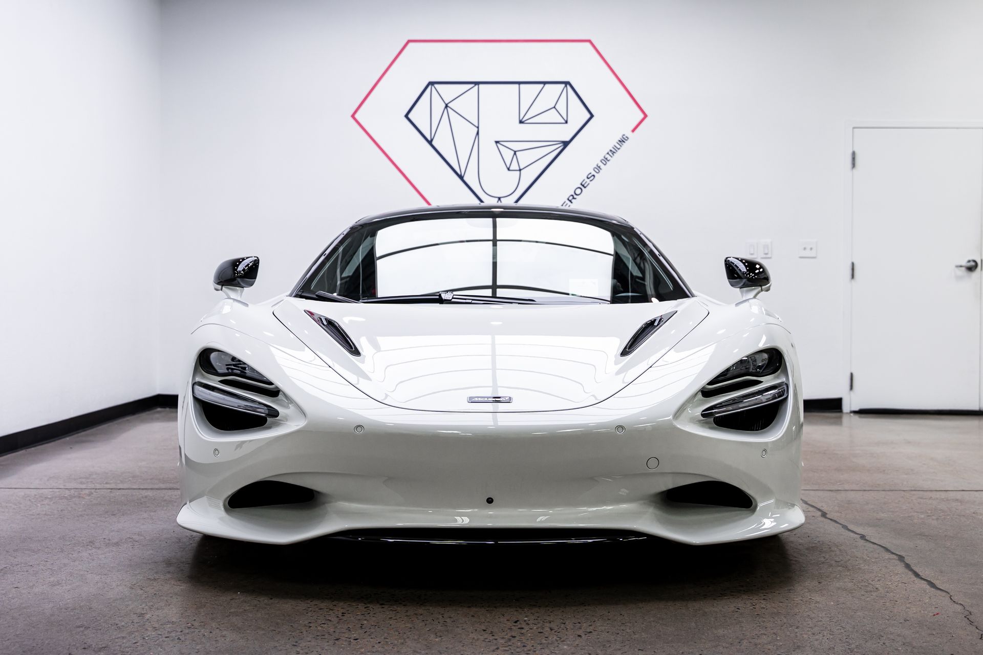 White McLaren sports car parked in a showroom.