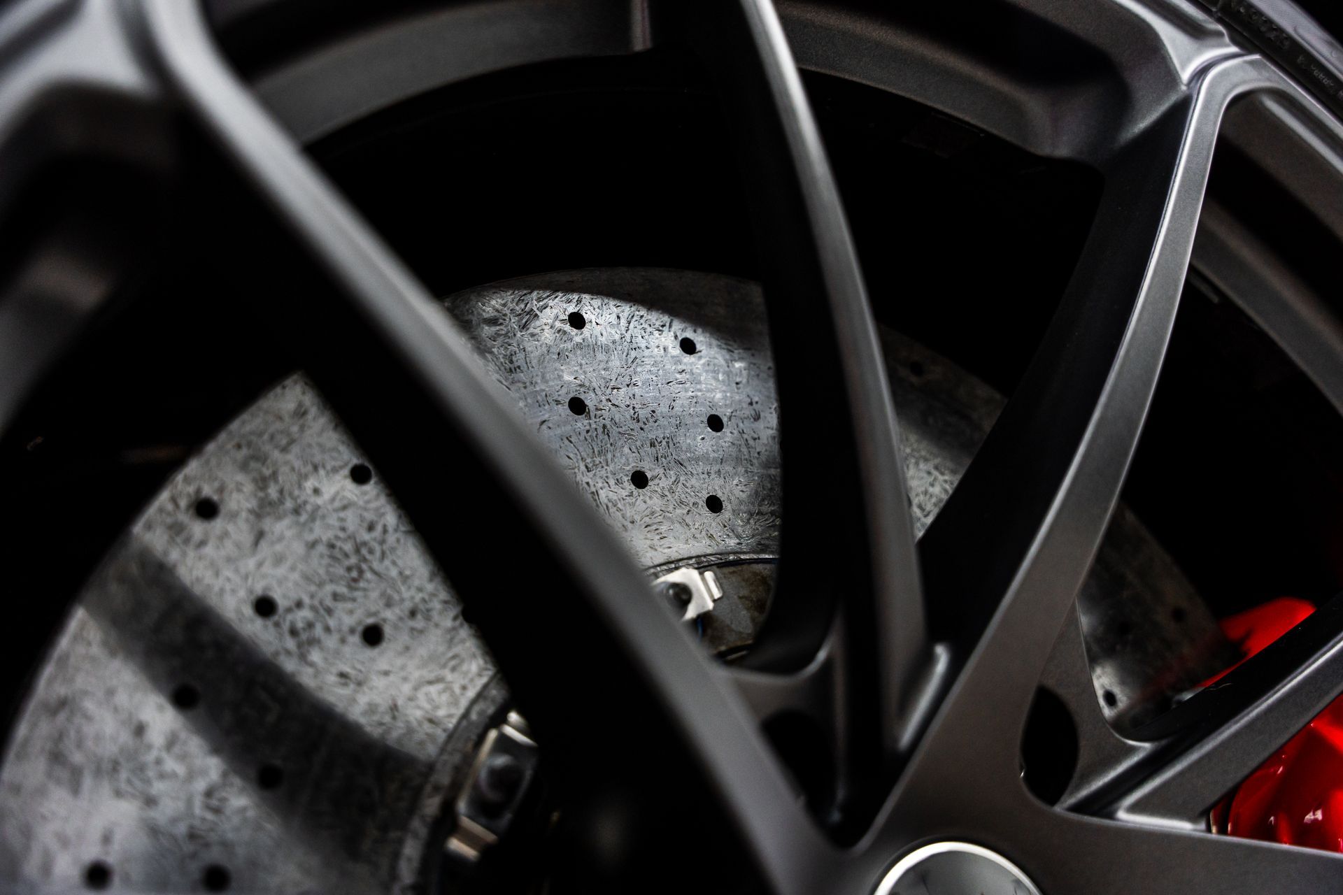 Close-up of a black car wheel and brake rotor with red caliper.