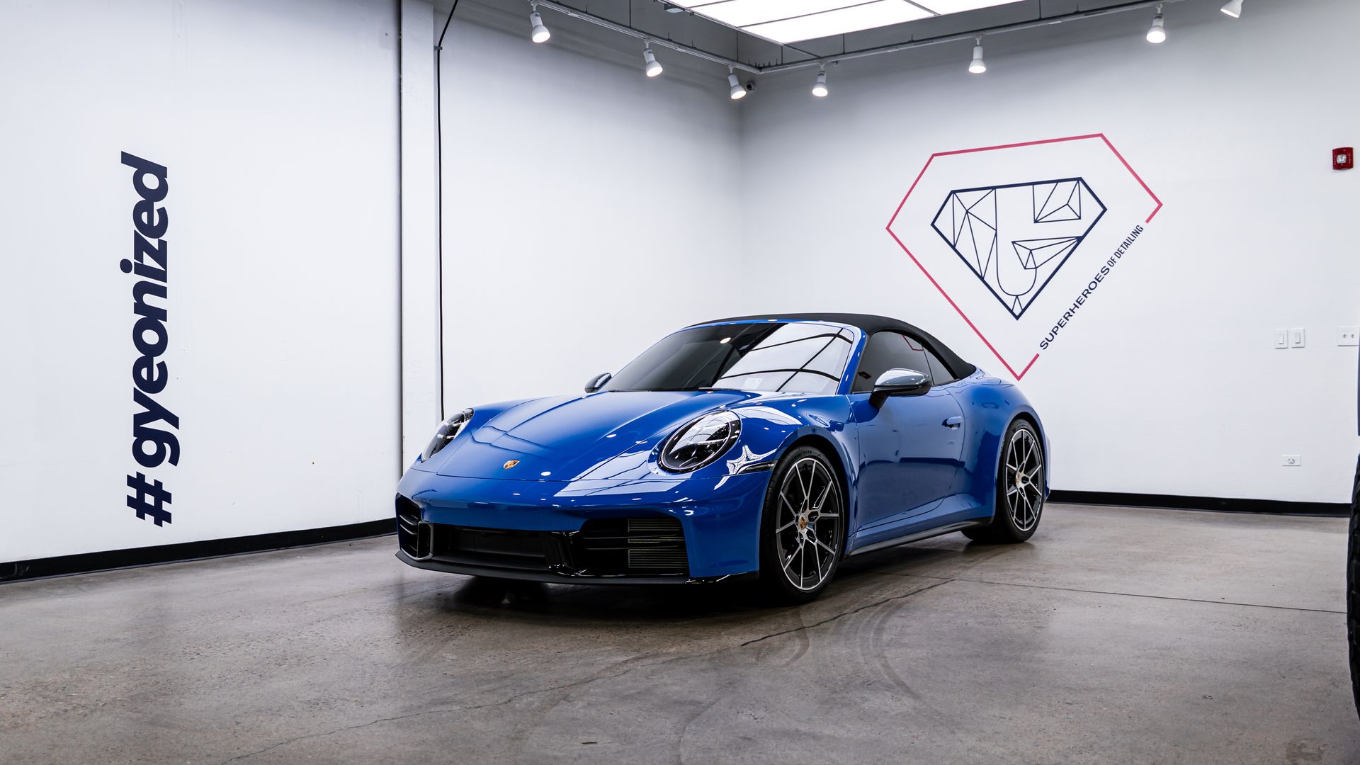 Blue Porsche sports car in a white garage with a diamond logo and