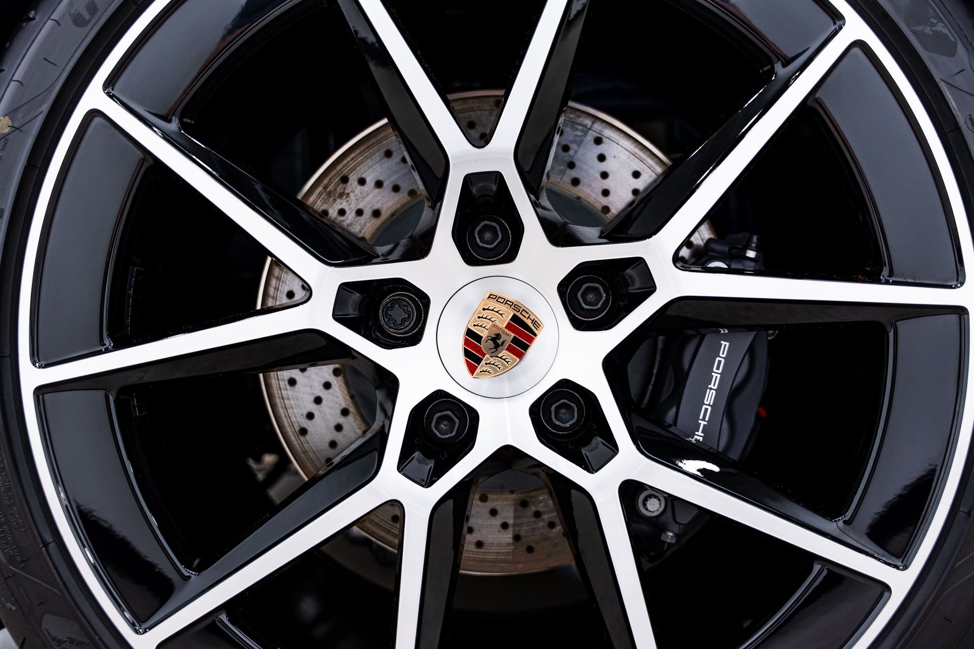 Close-up of a black and silver Porsche wheel with the Porsche emblem in the center.