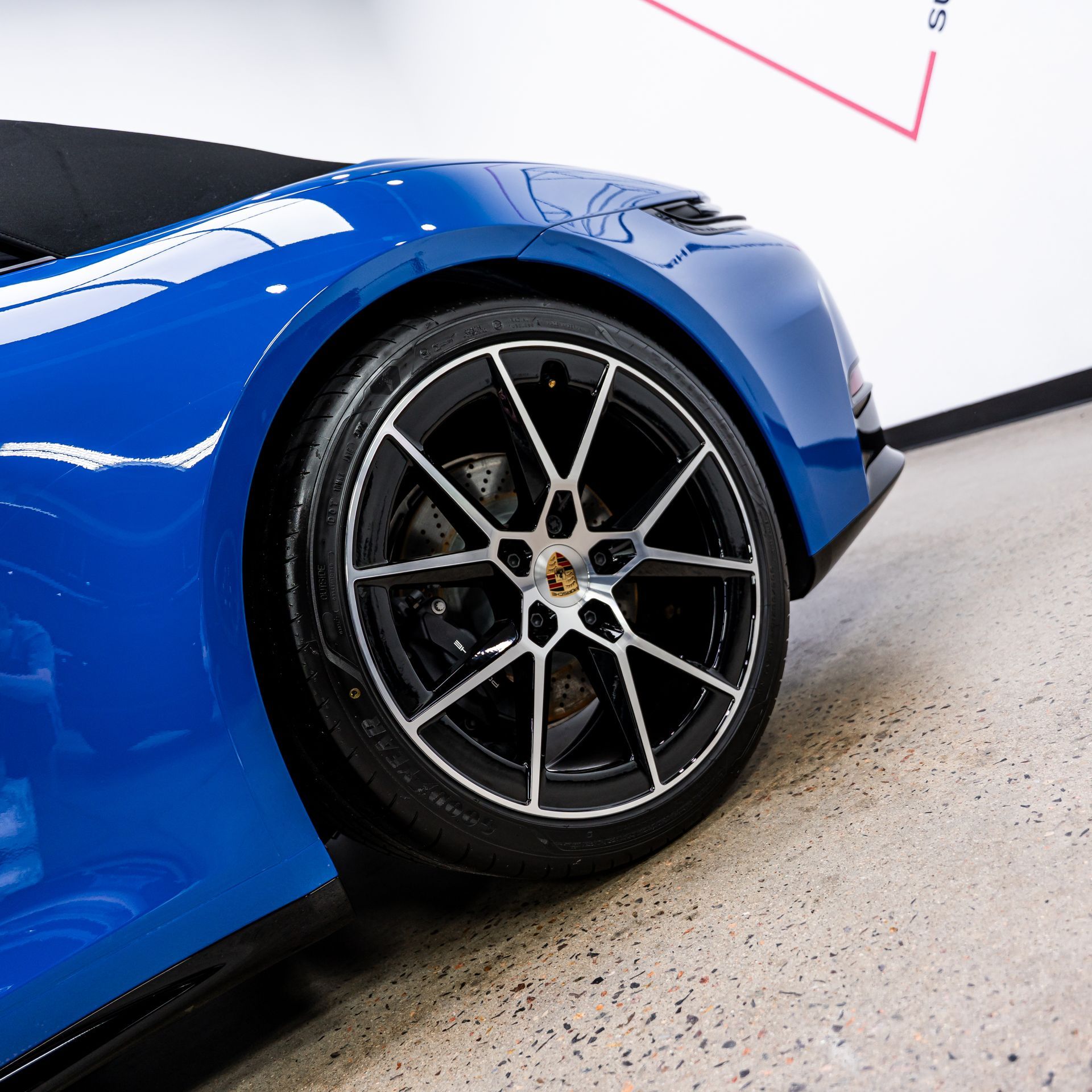 Blue sports car wheel with black and silver rim, parked on concrete.