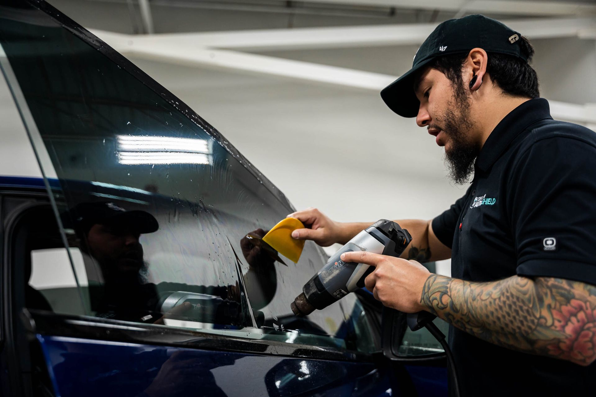 A man is applying tinted glass to a car window.
