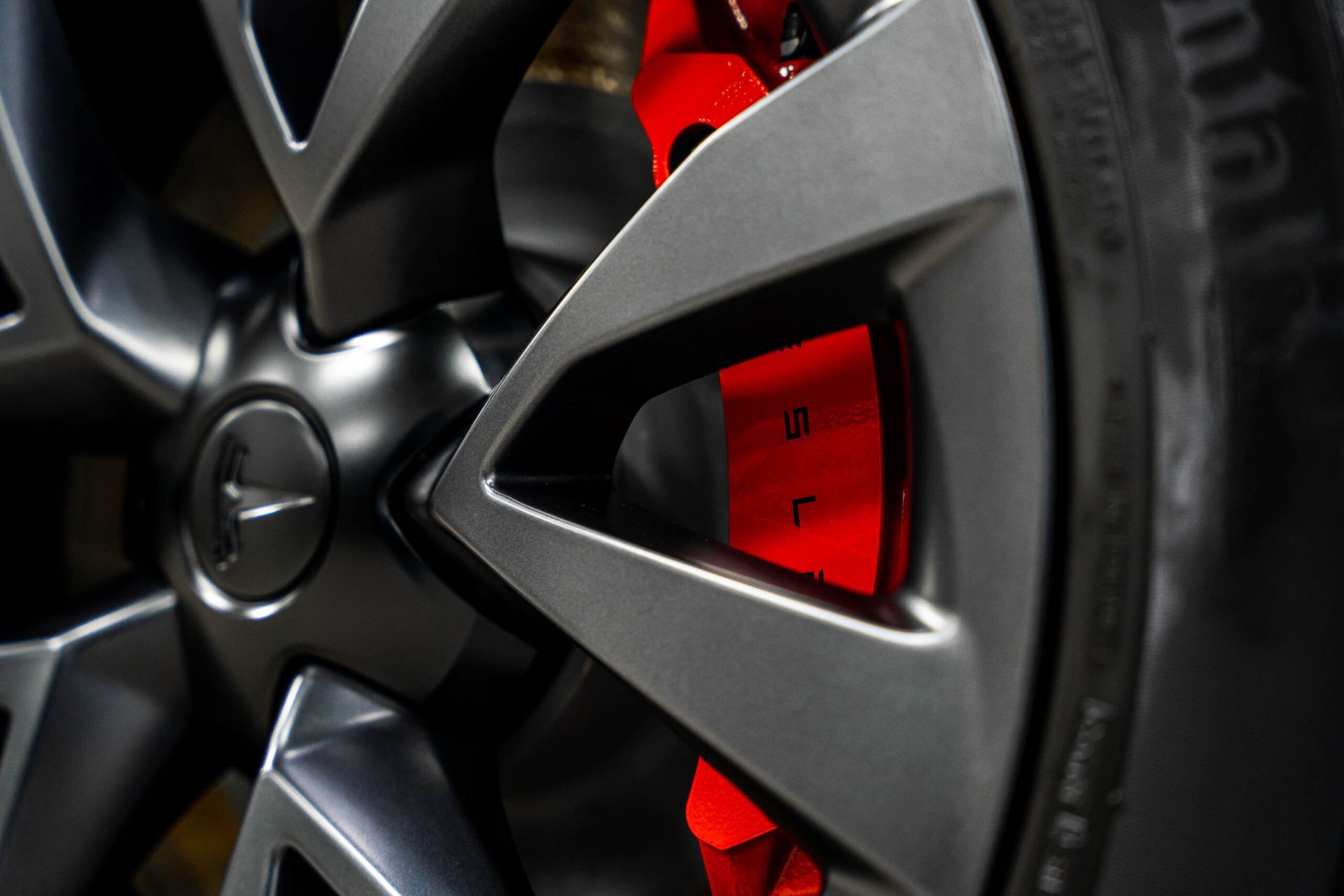 A close up of a tesla model 3 wheel with red brake calipers.