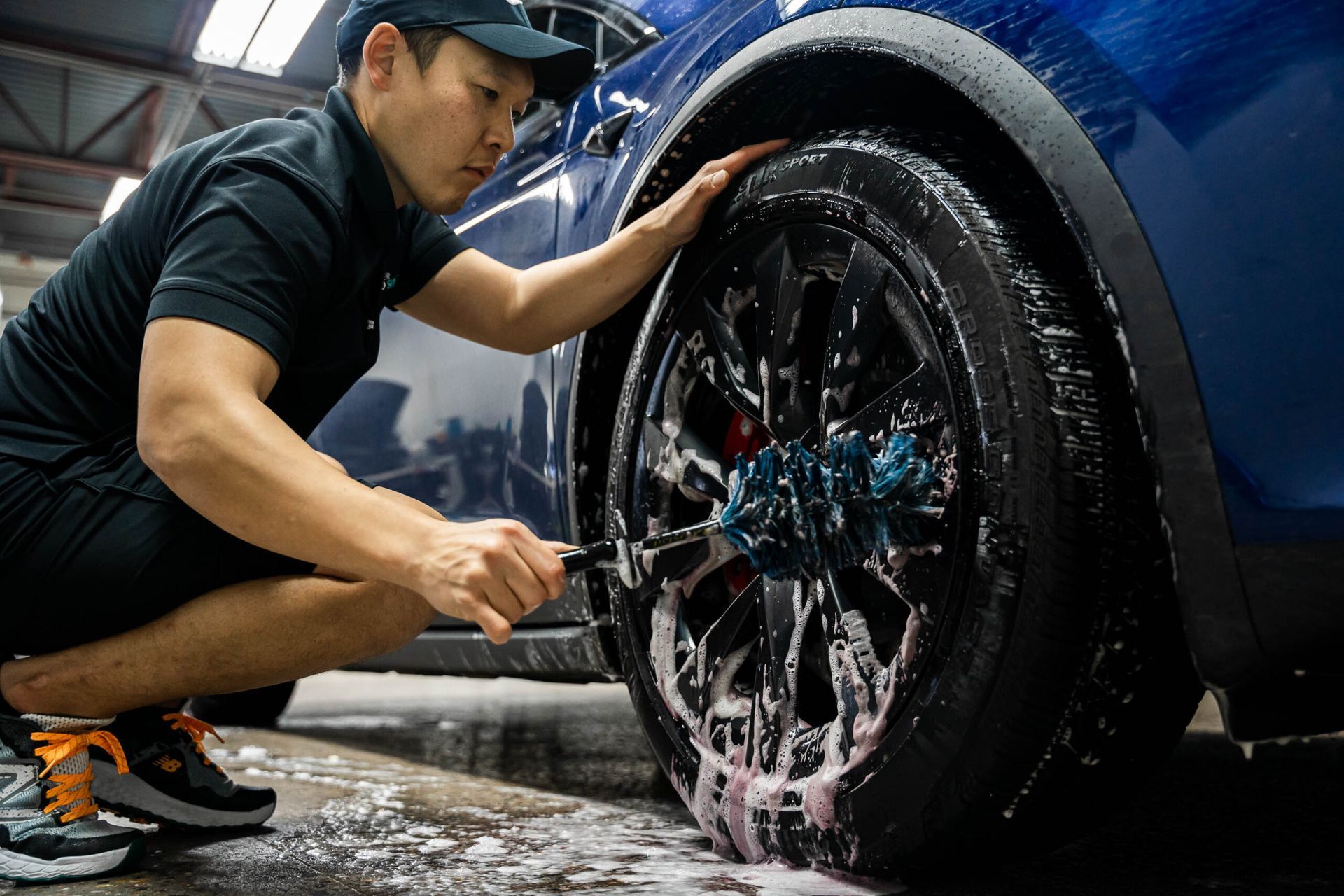 A man is cleaning a car wheel with a brush.