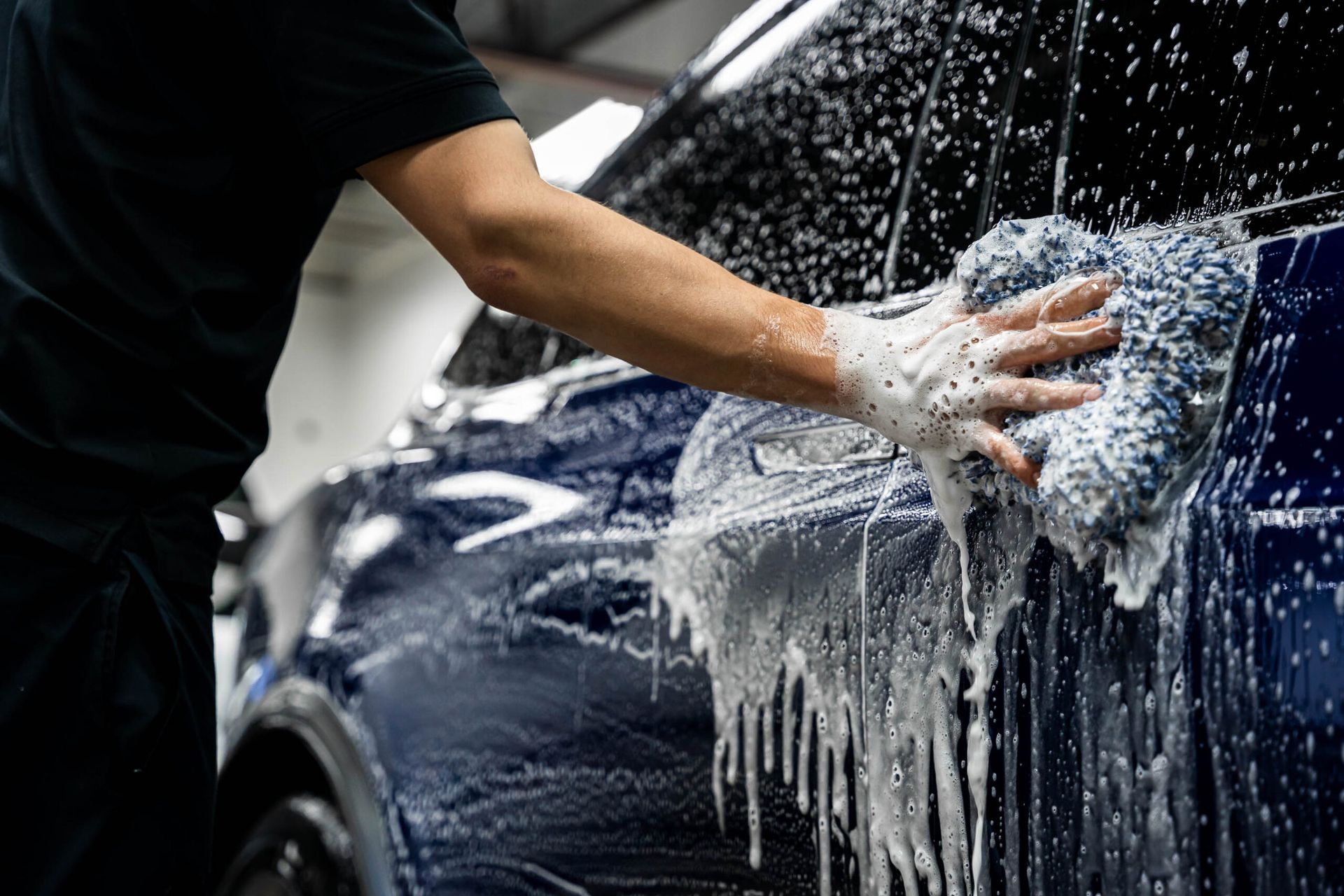 A man is washing a car with a towel and soap.
