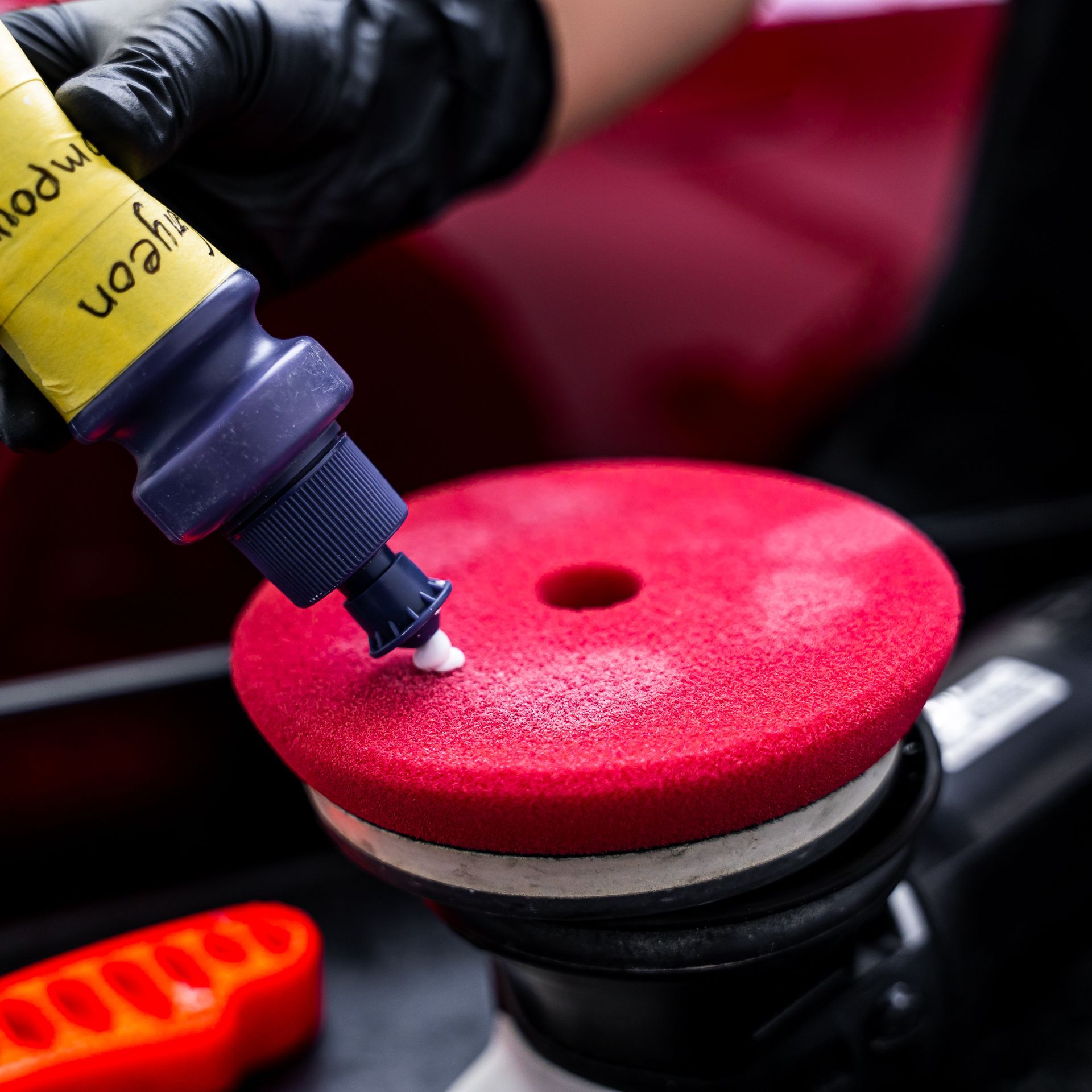 A person is applying polish to a red sponge