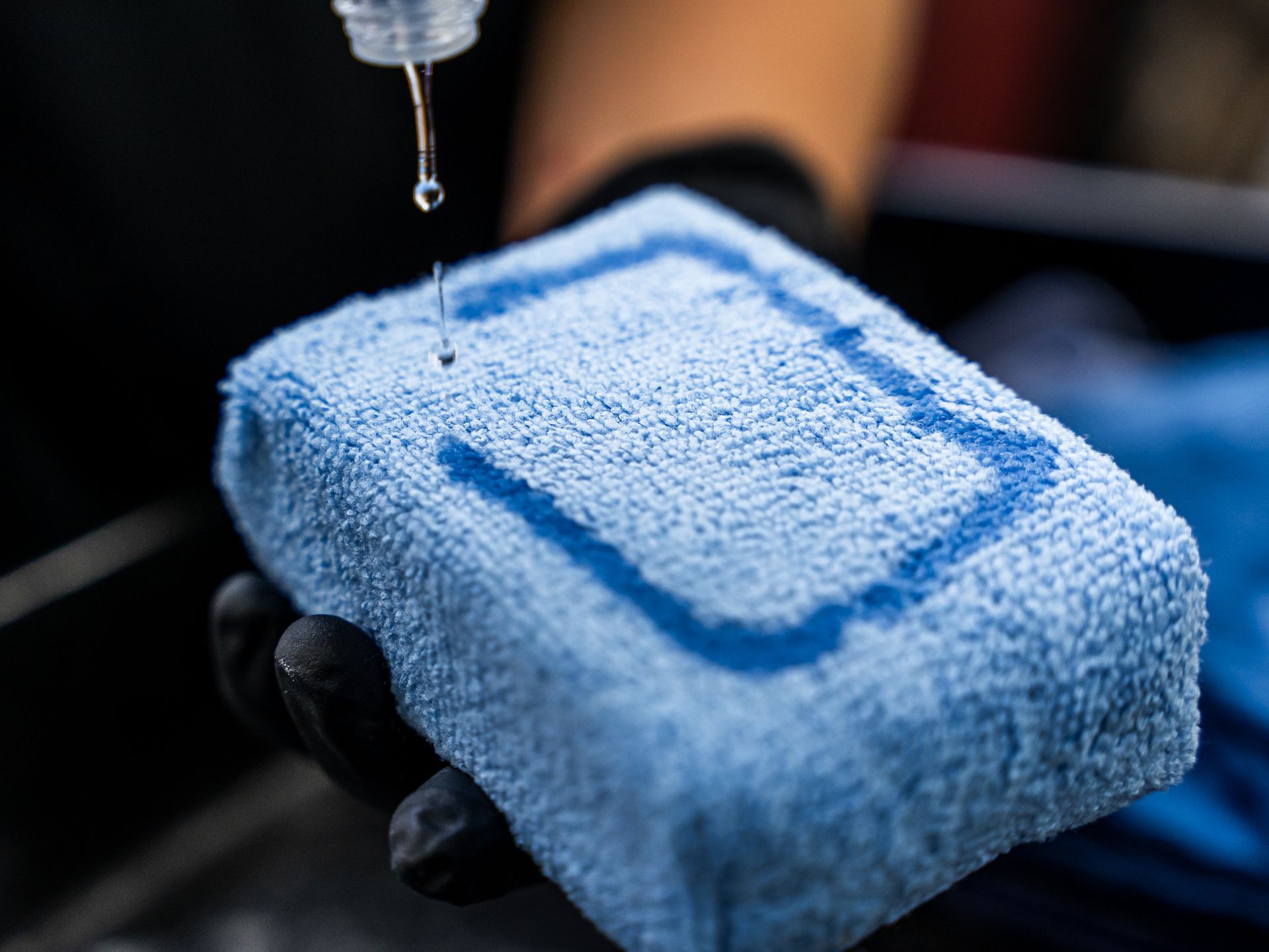 A person is holding a blue sponge with water dripping from it.