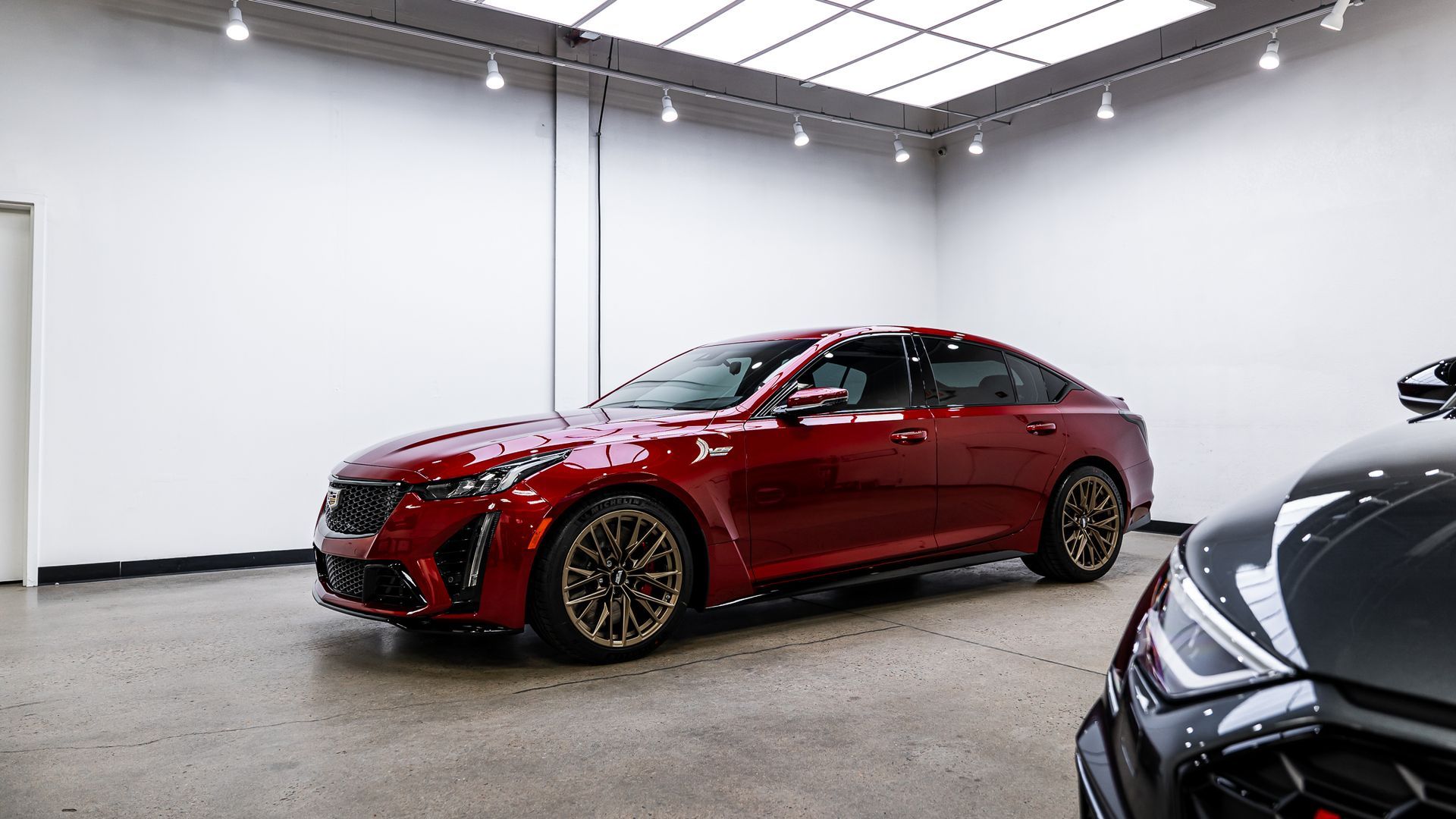 A red car is parked in a garage next to a black car.