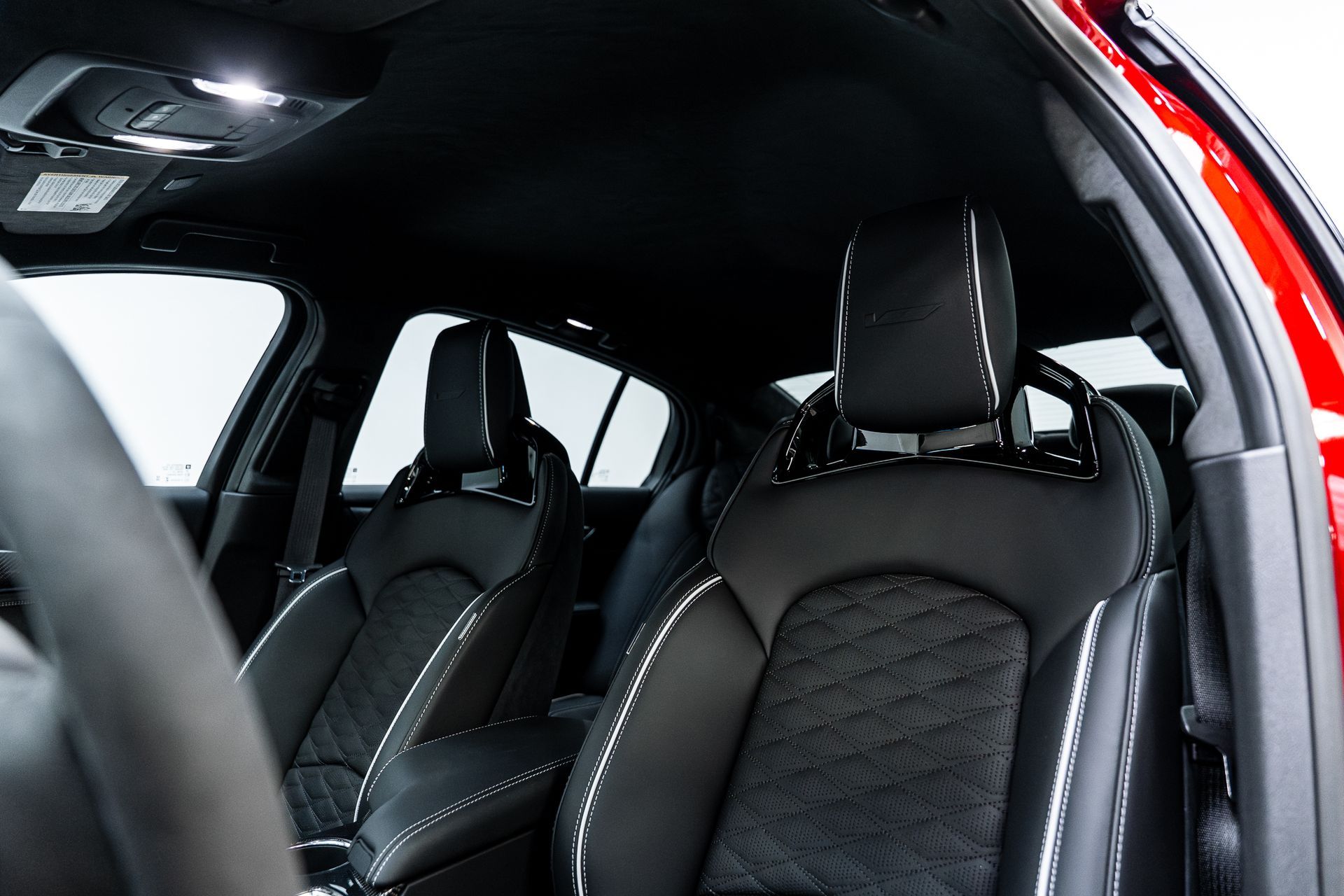 The interior of a red car with black seats and a steering wheel.