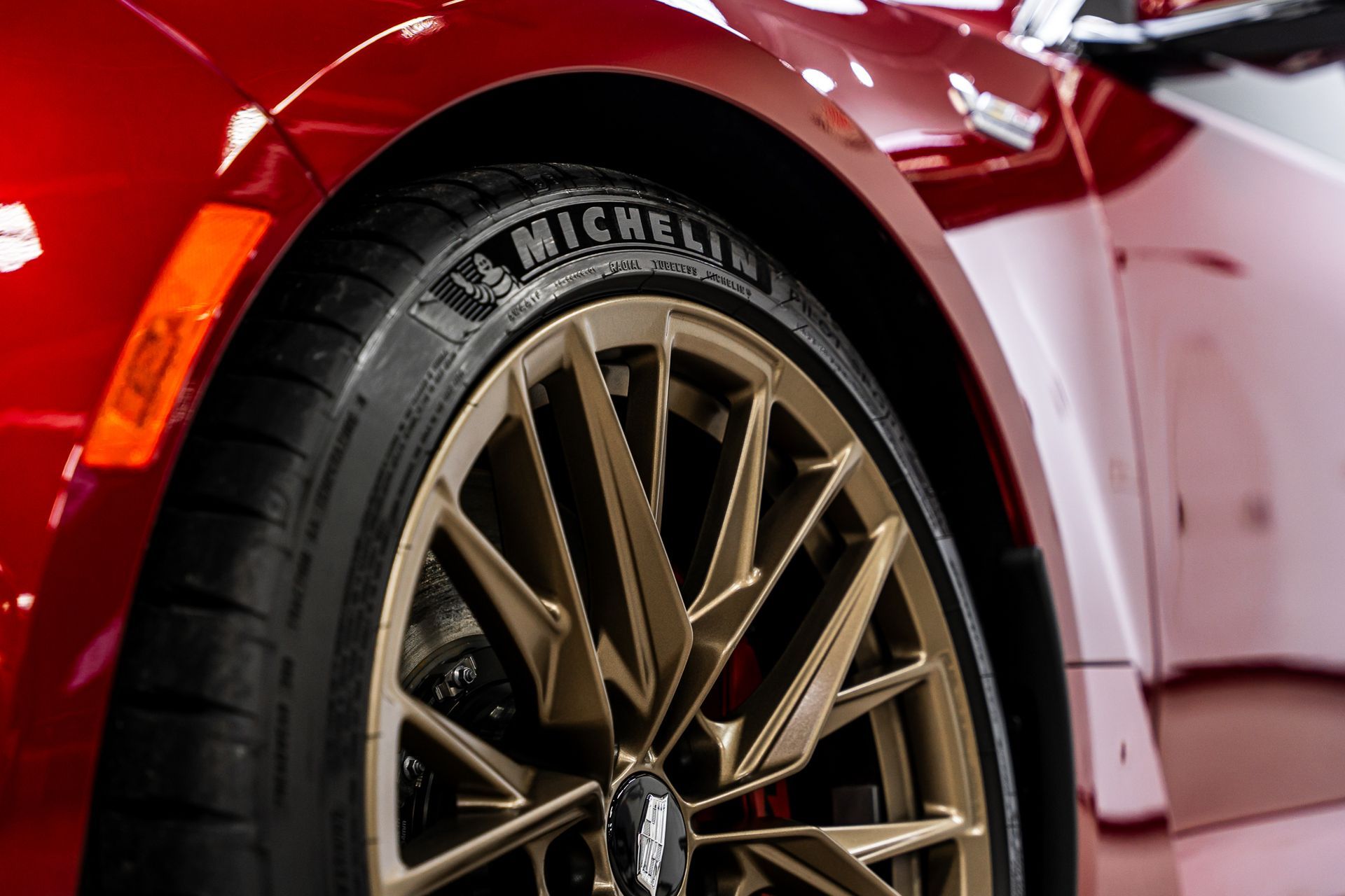 A close up of a red car with a michelin tire on it.