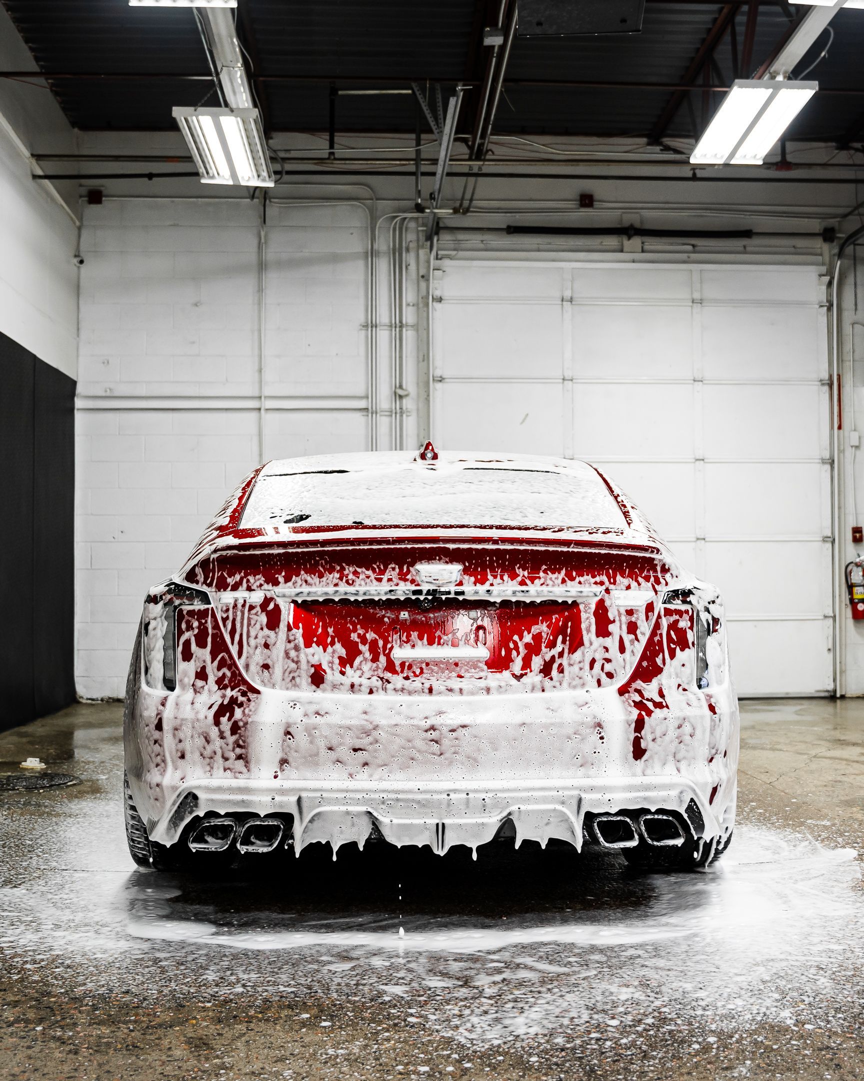 A car is covered in foam in a garage.