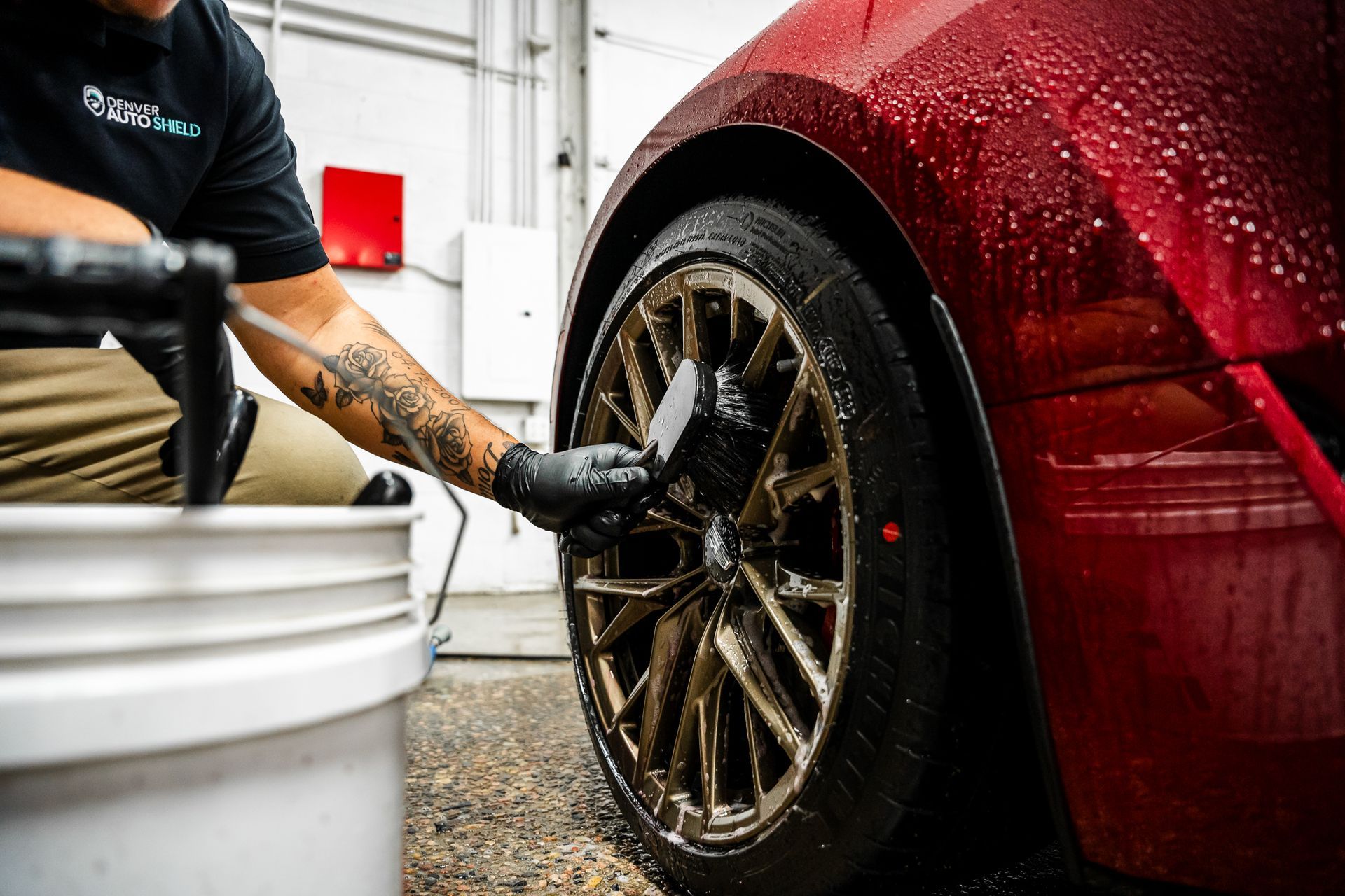 A man is cleaning a car wheel with a brush.