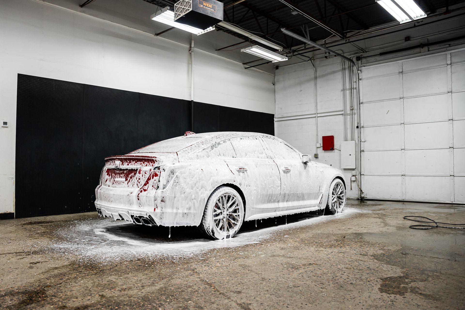 A car is covered in foam in a garage.
