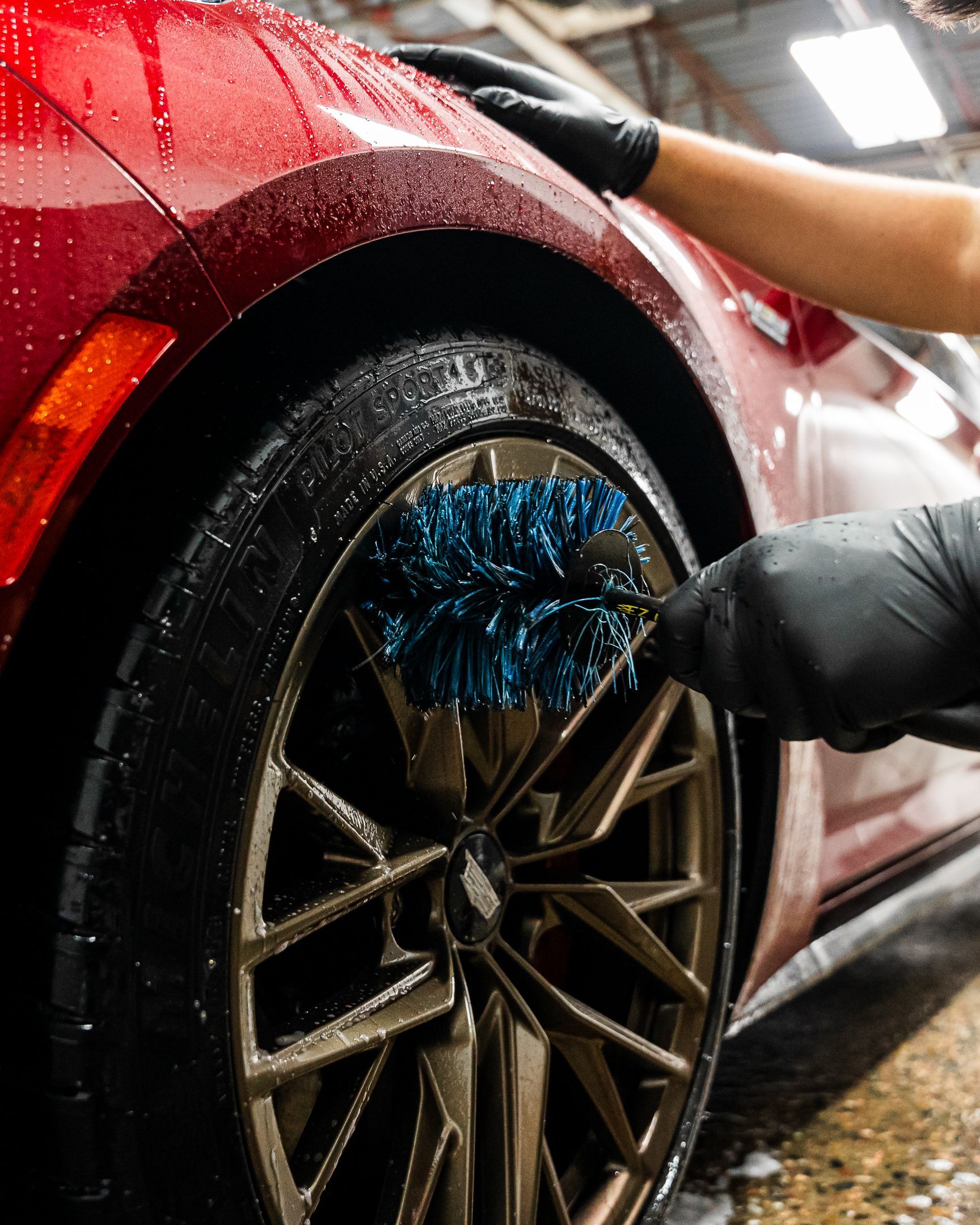 A person is cleaning a car wheel with a brush.