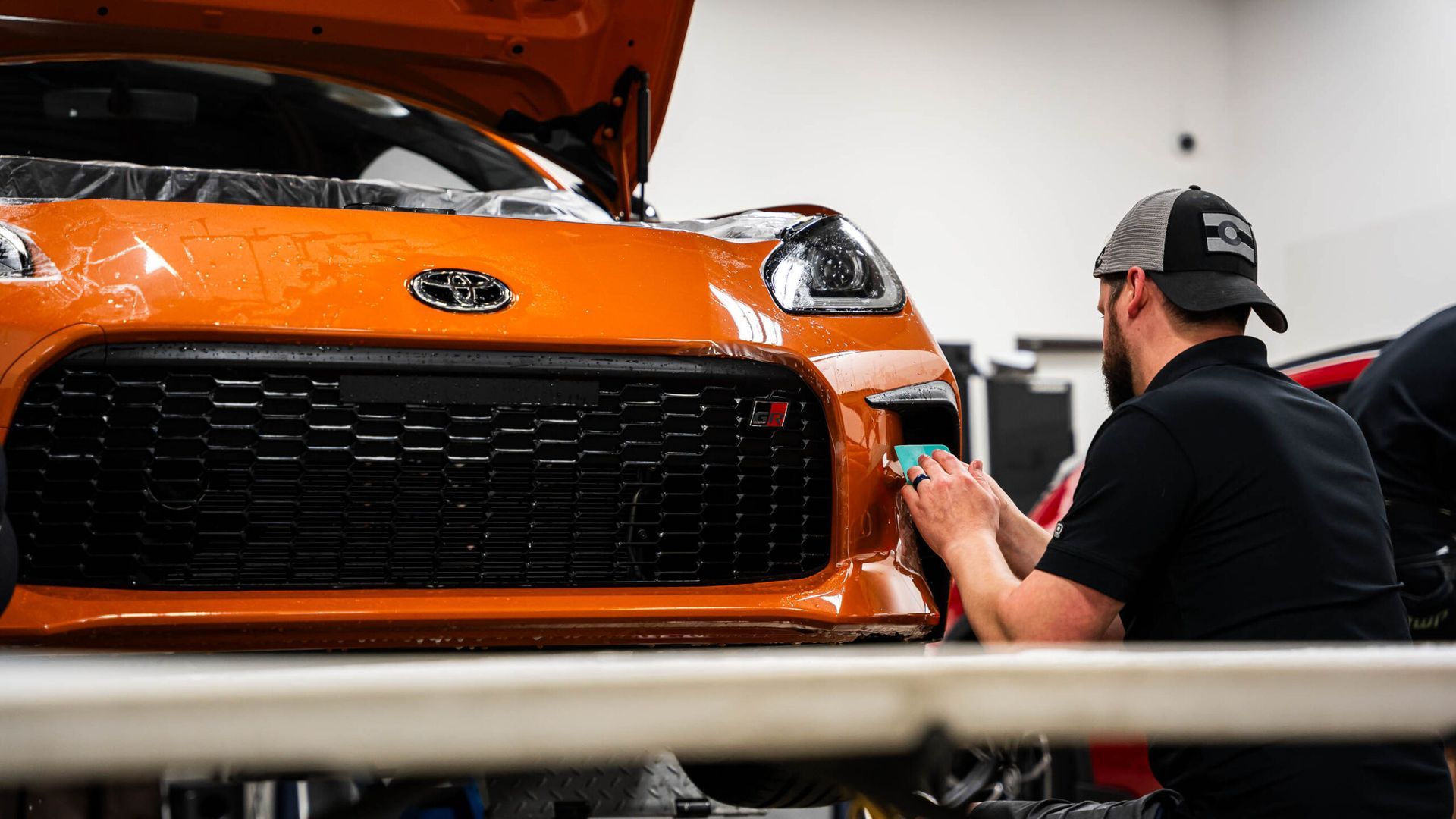 A man is working on the front of a car in a garage.