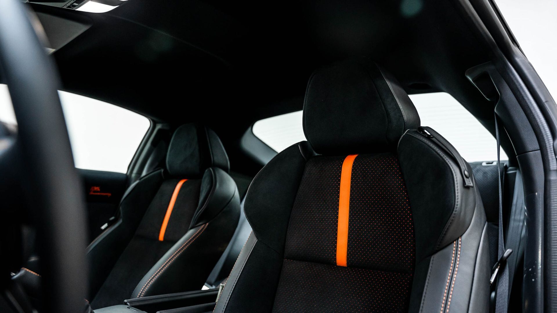 The interior of a black car with orange stripes on the seats.