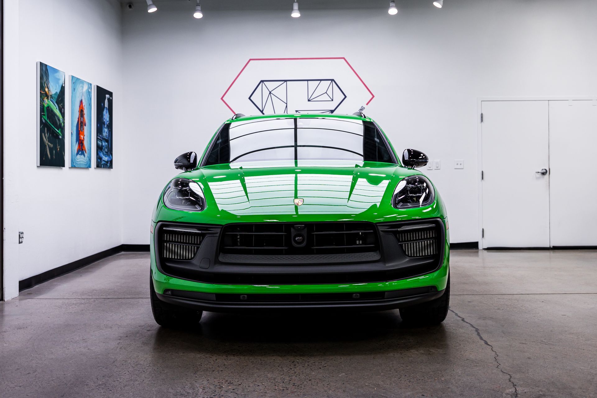 Green Porsche Macan SUV in a brightly lit showroom.